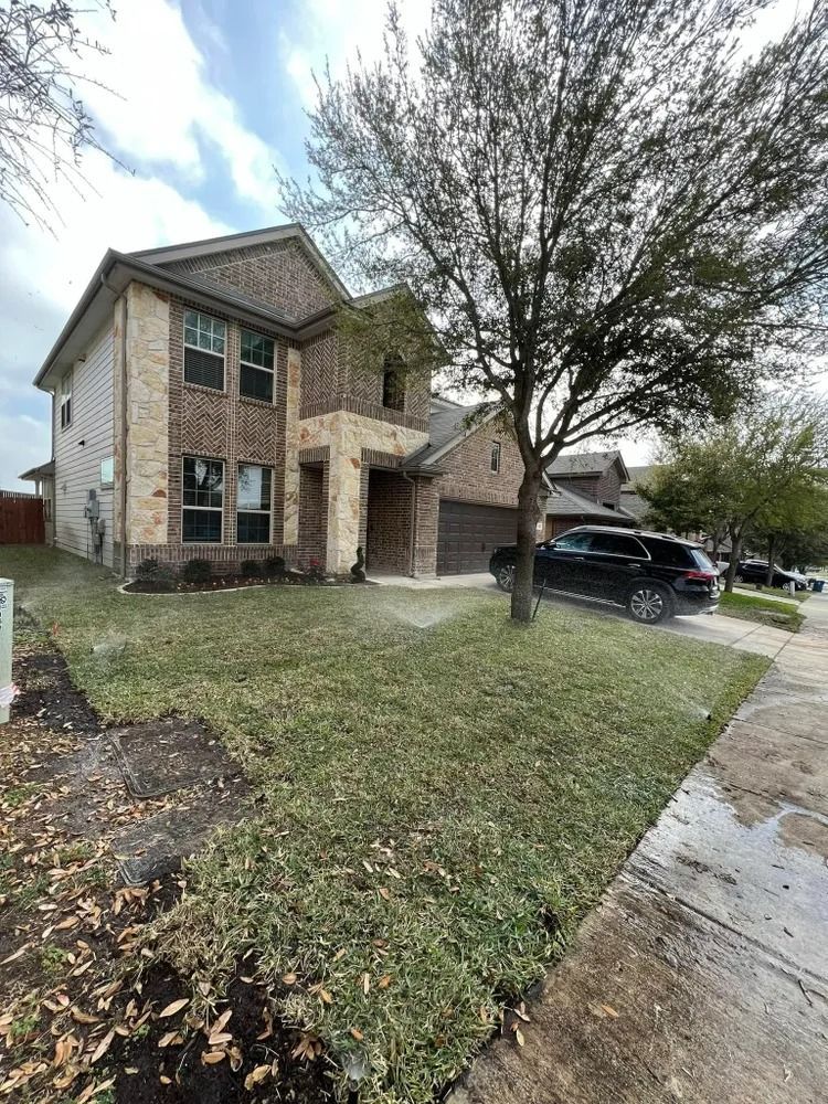 Two-story brick house with a lawn and a black car parked in the driveway.