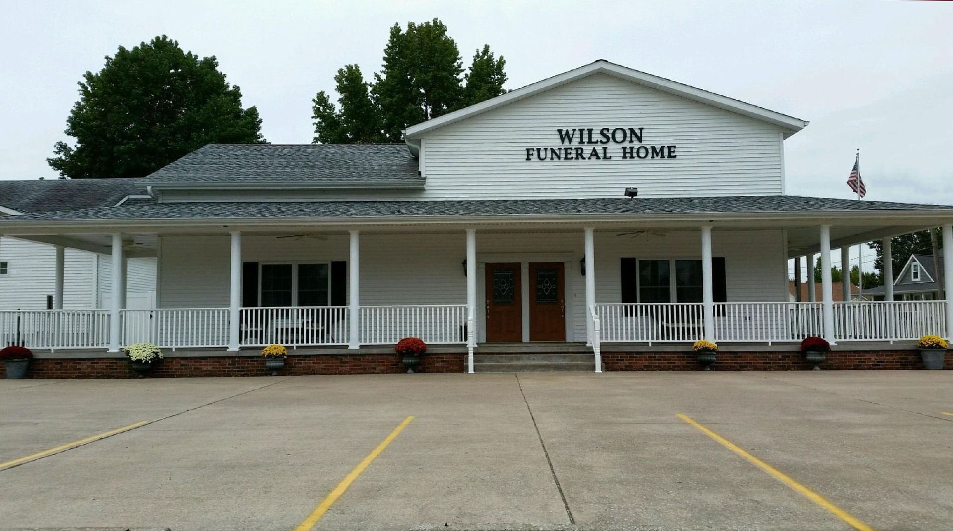 Wilson Funeral Home, a white one-story building with a porch and a parking lot, with a cloudy sky.
