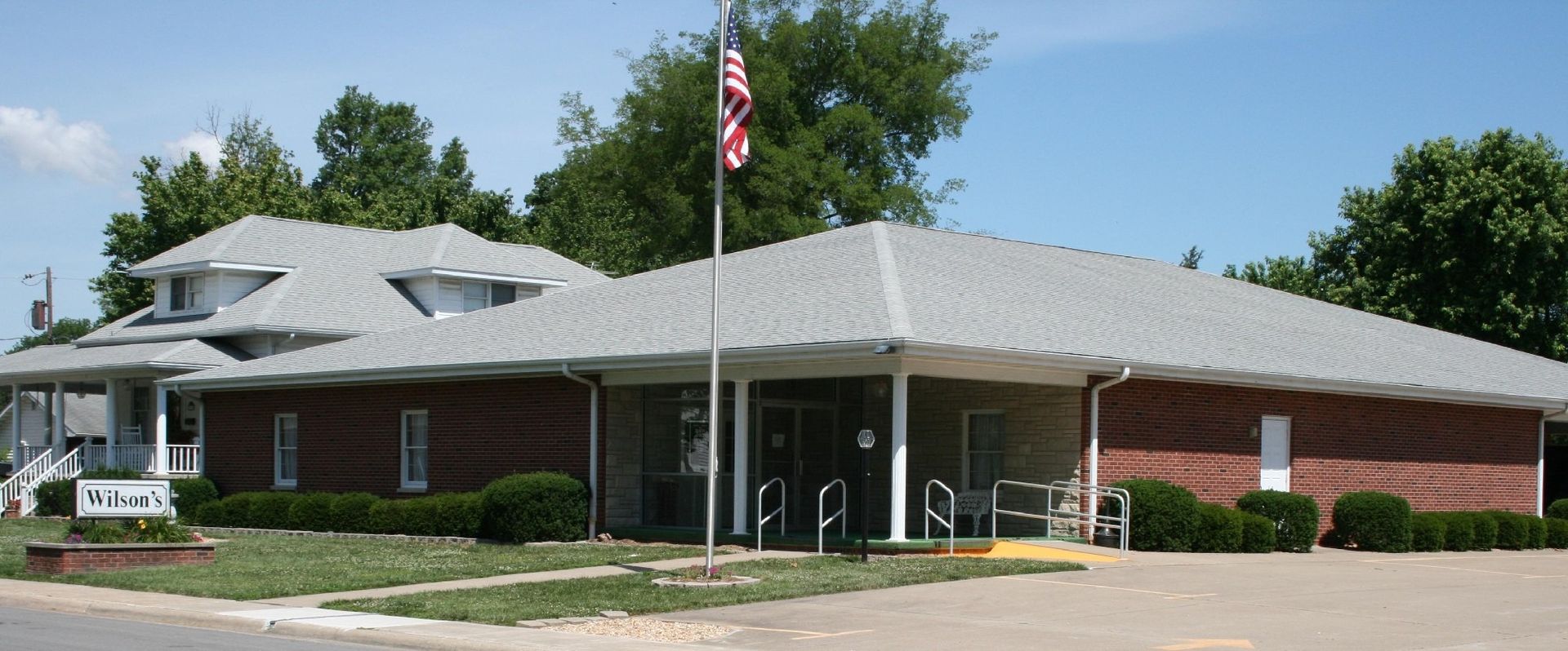 A brick building with a gray roof and a flagpole with an American flag.