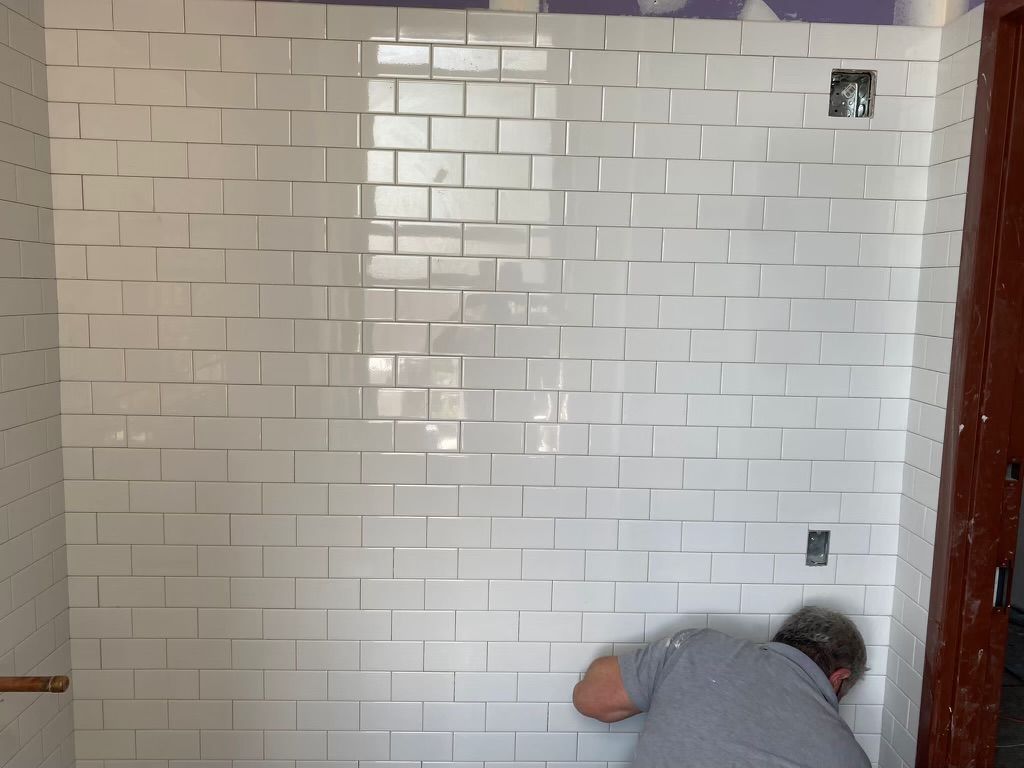 A man is working on a white brick wall in a bathroom