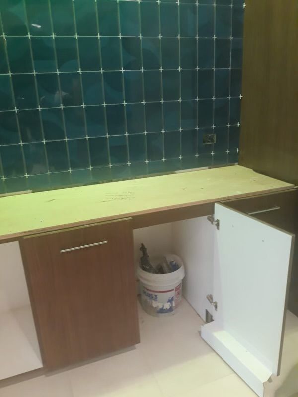 A bucket of paint sits under a kitchen counter