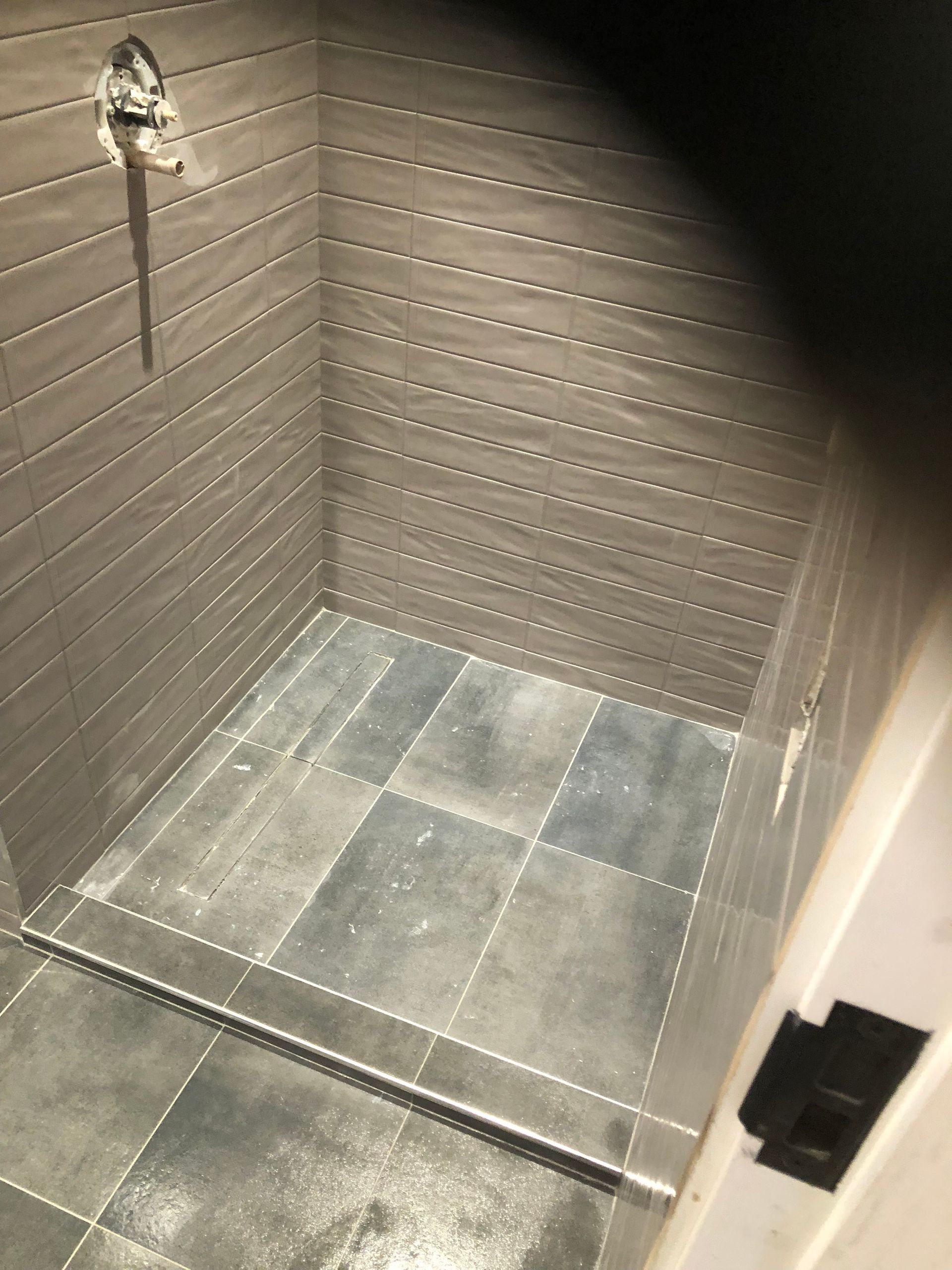 A bathroom with a walk in shower and a tiled floor.