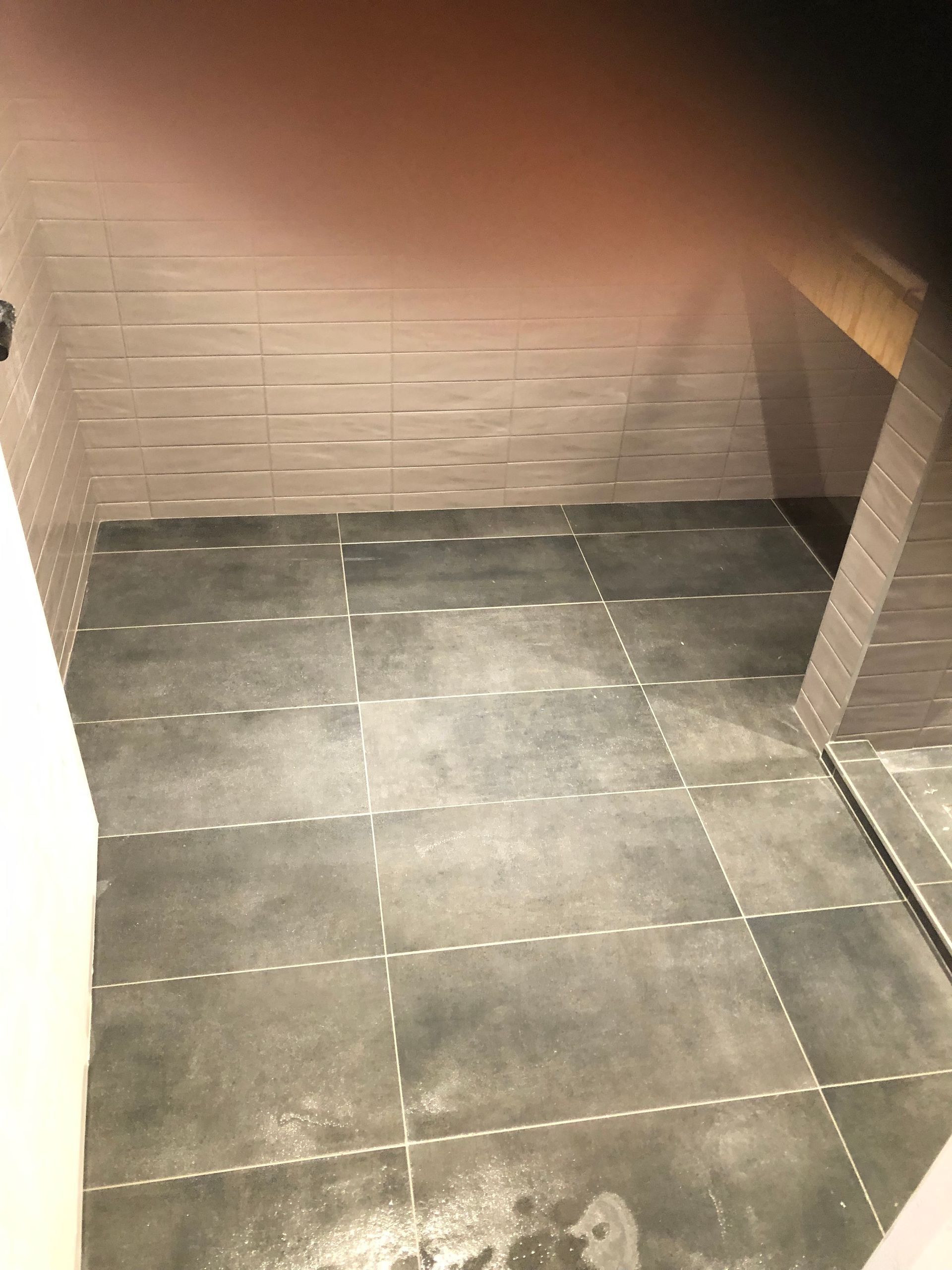A bathroom with a tiled floor and a mirror.