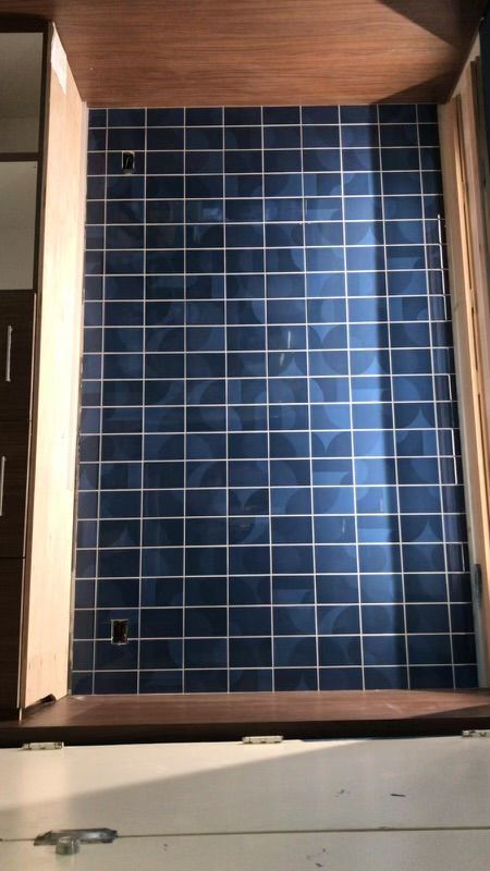 A room with blue tiles on the wall and a window.