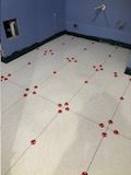 A white tile floor with red paw prints on it in a bathroom.