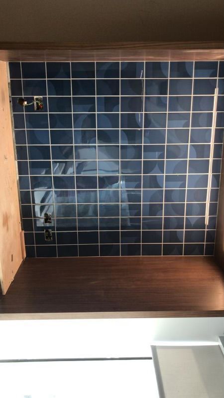 A kitchen with blue tiles on the wall and a wooden counter top.