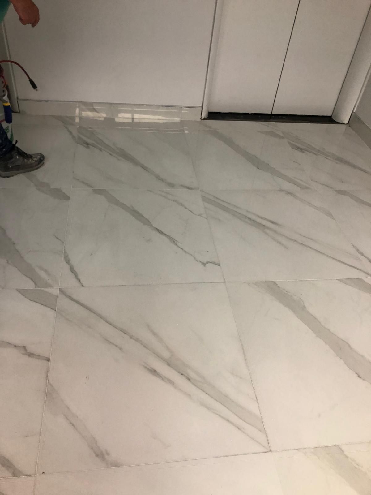 A person is standing on a marble floor in a room.