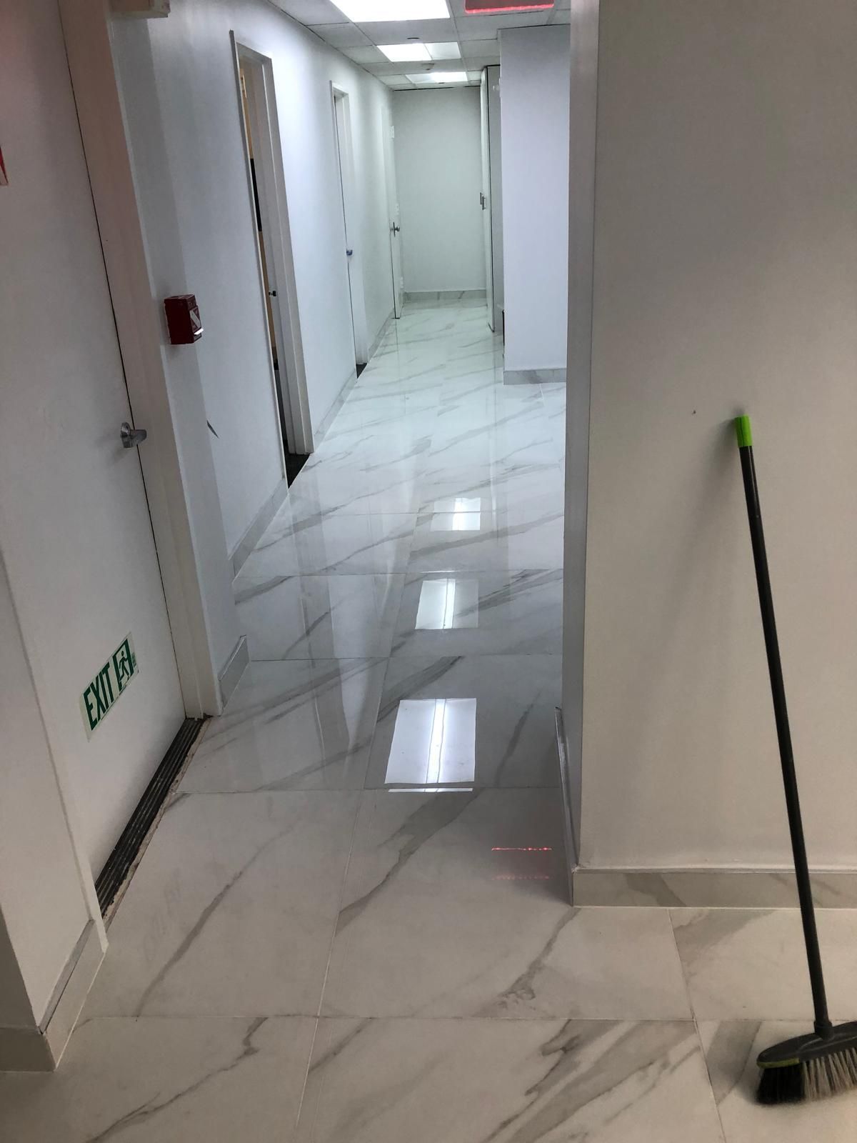 A broom is sitting on the floor in a hallway.