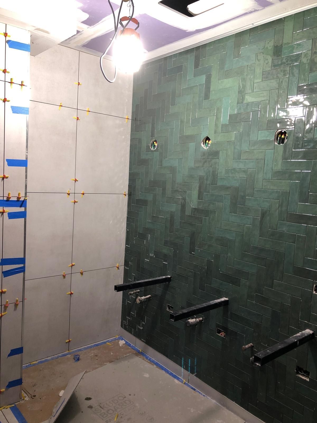 A bathroom with green tiles and a light on the ceiling.