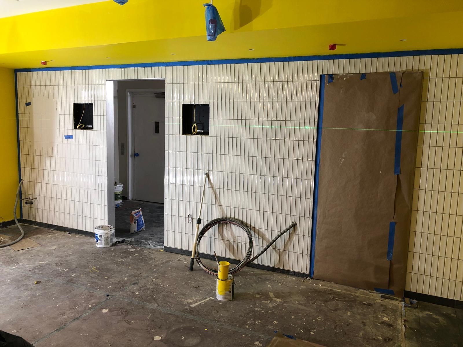 A room with yellow walls and white tiles is being remodeled.