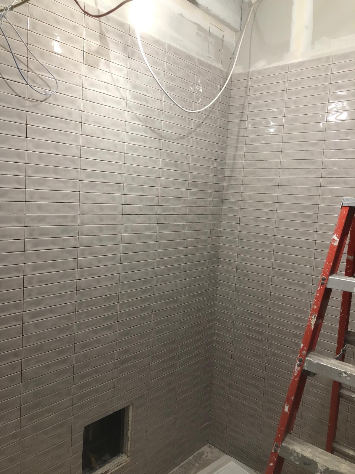 A bathroom under construction with a ladder in the corner.