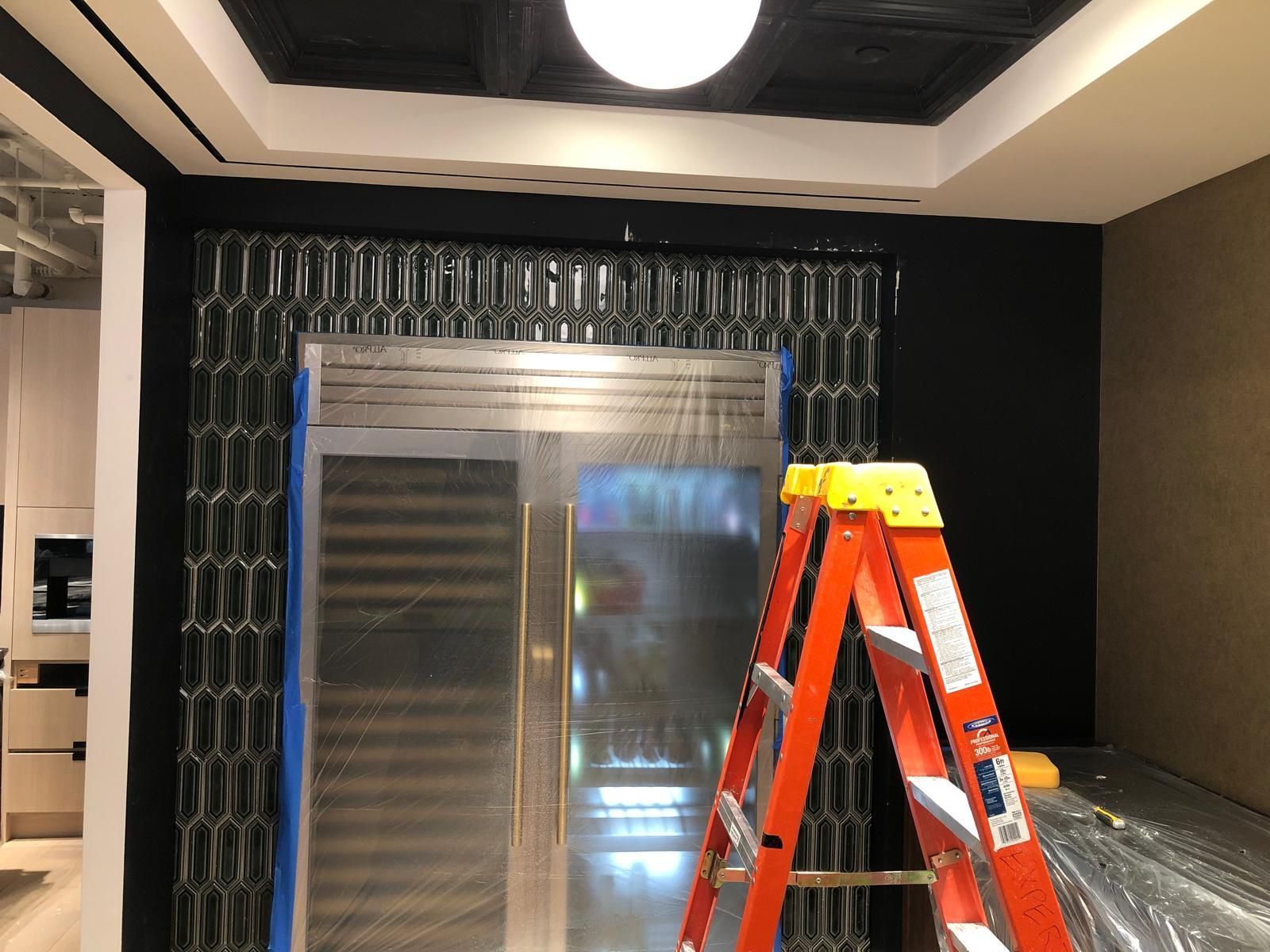 A ladder is sitting in front of a refrigerator in a room.
