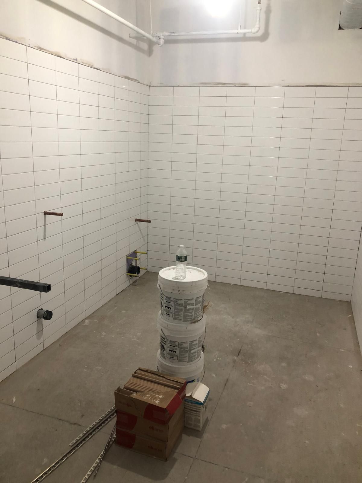 A room with white brick walls and a stack of buckets on the floor.