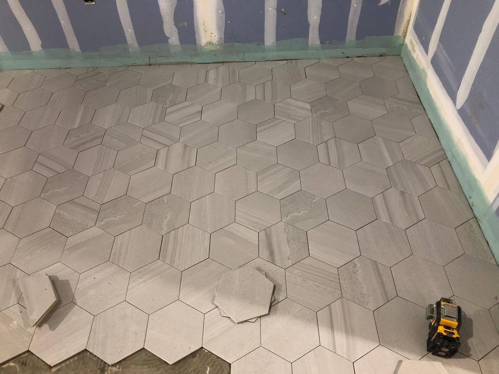 A hexagon tile floor is being installed in a bathroom.