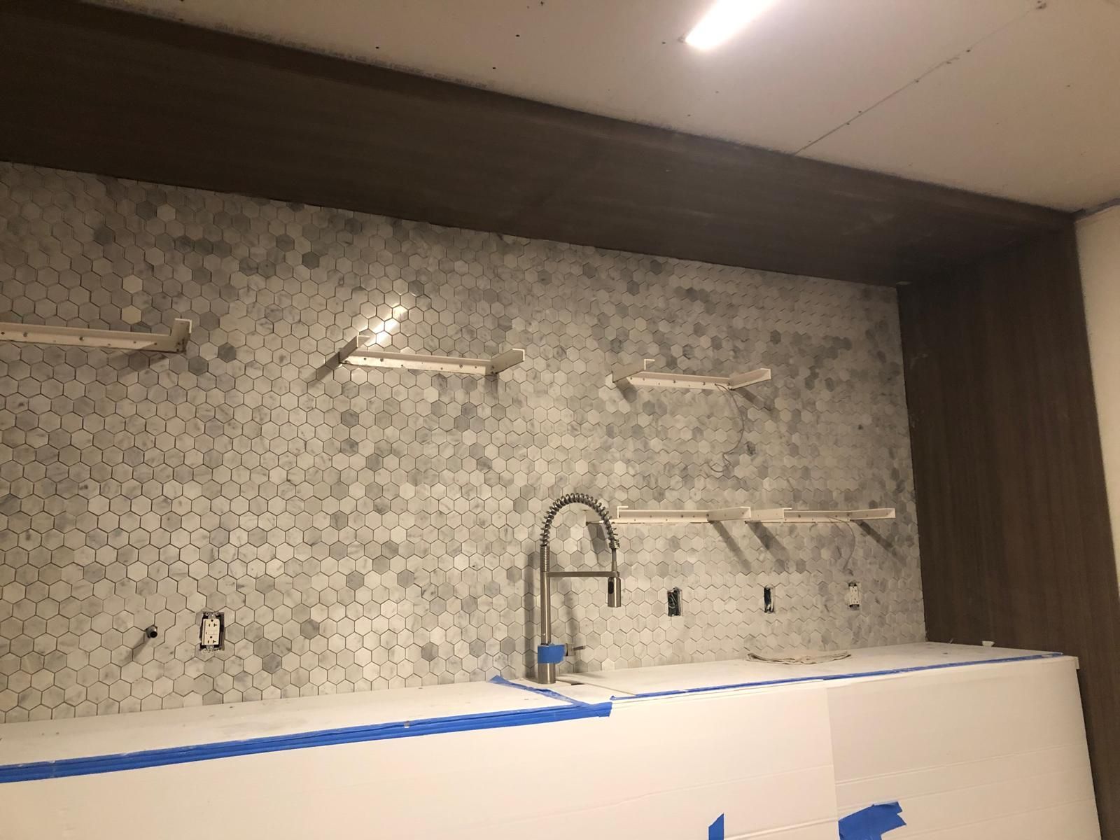 A kitchen under construction with a sink and shelves.