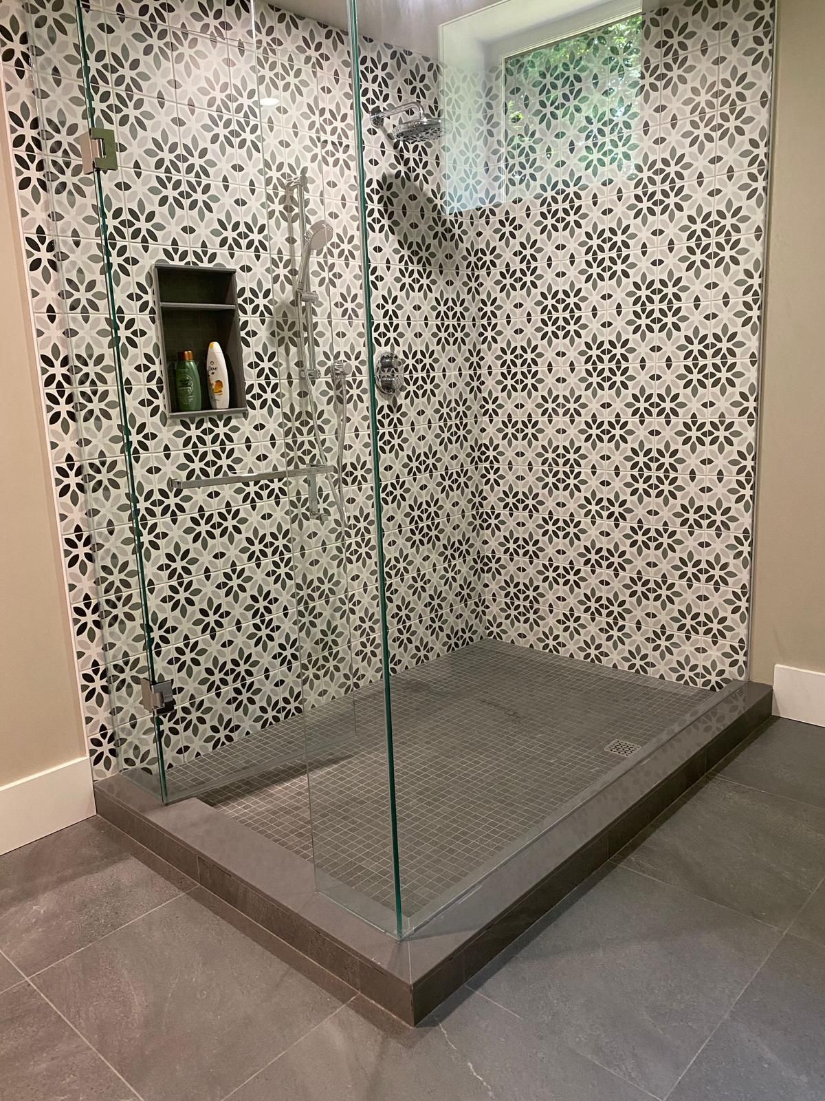 A walk in shower with a glass door and a tiled wall.