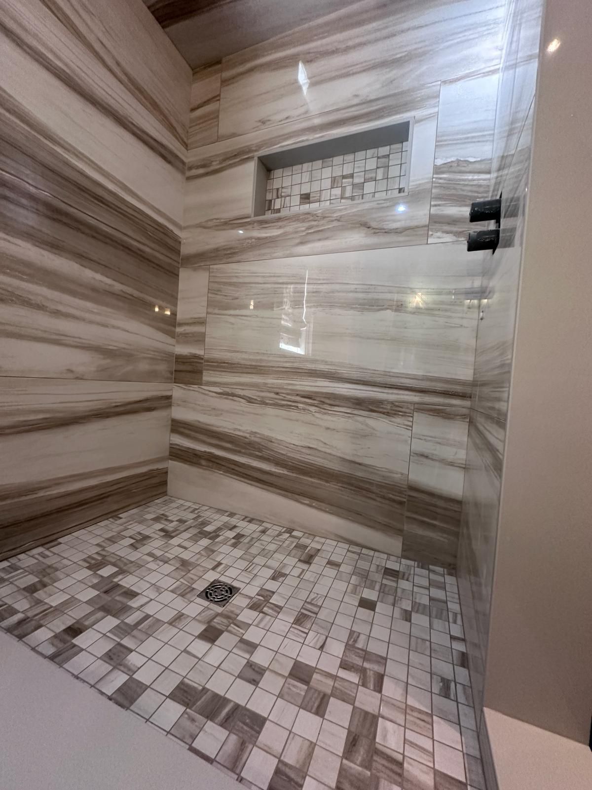 A bathroom with marble tiles and a walk in shower.