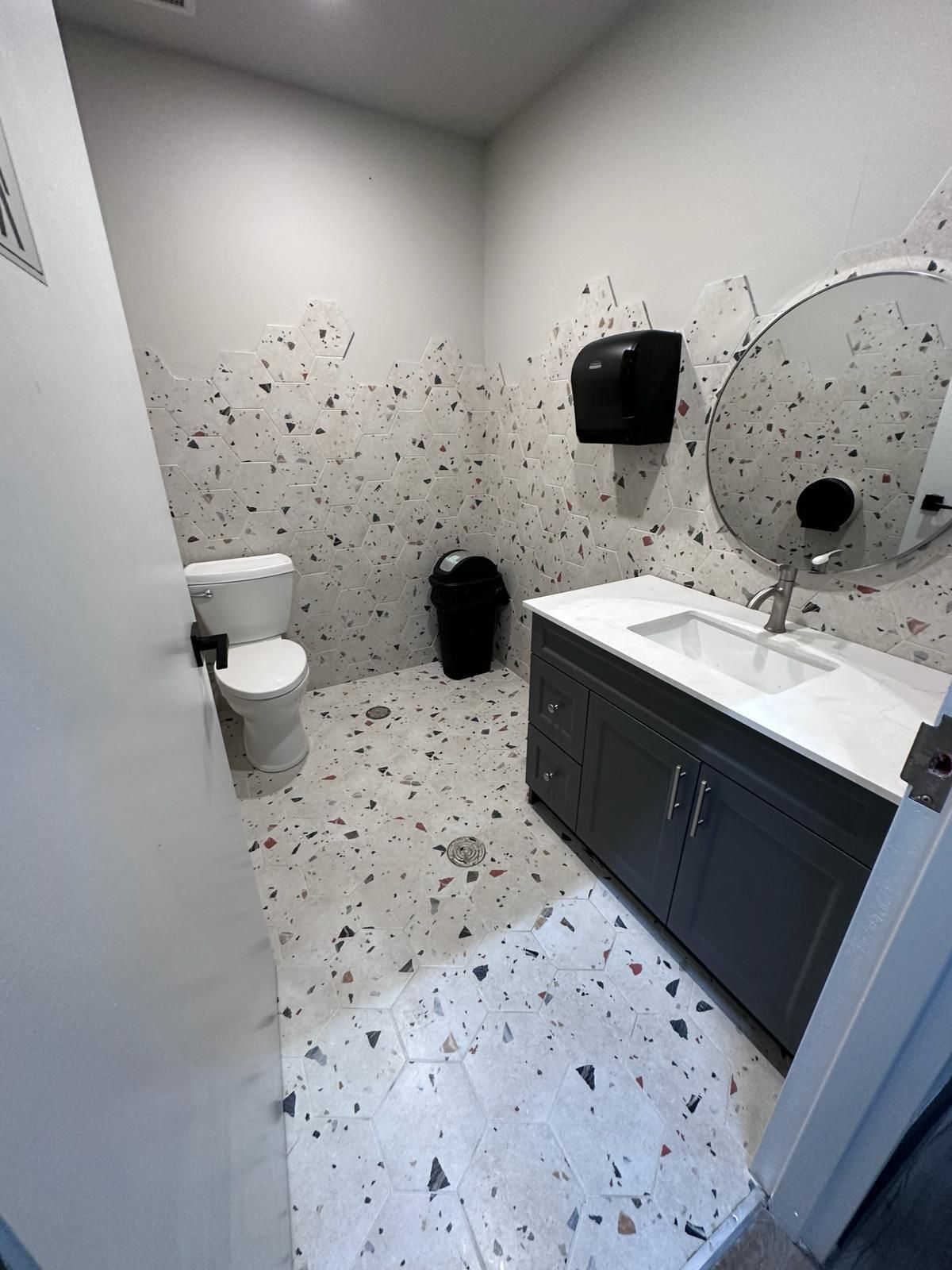 A bathroom with a toilet , sink and mirror.