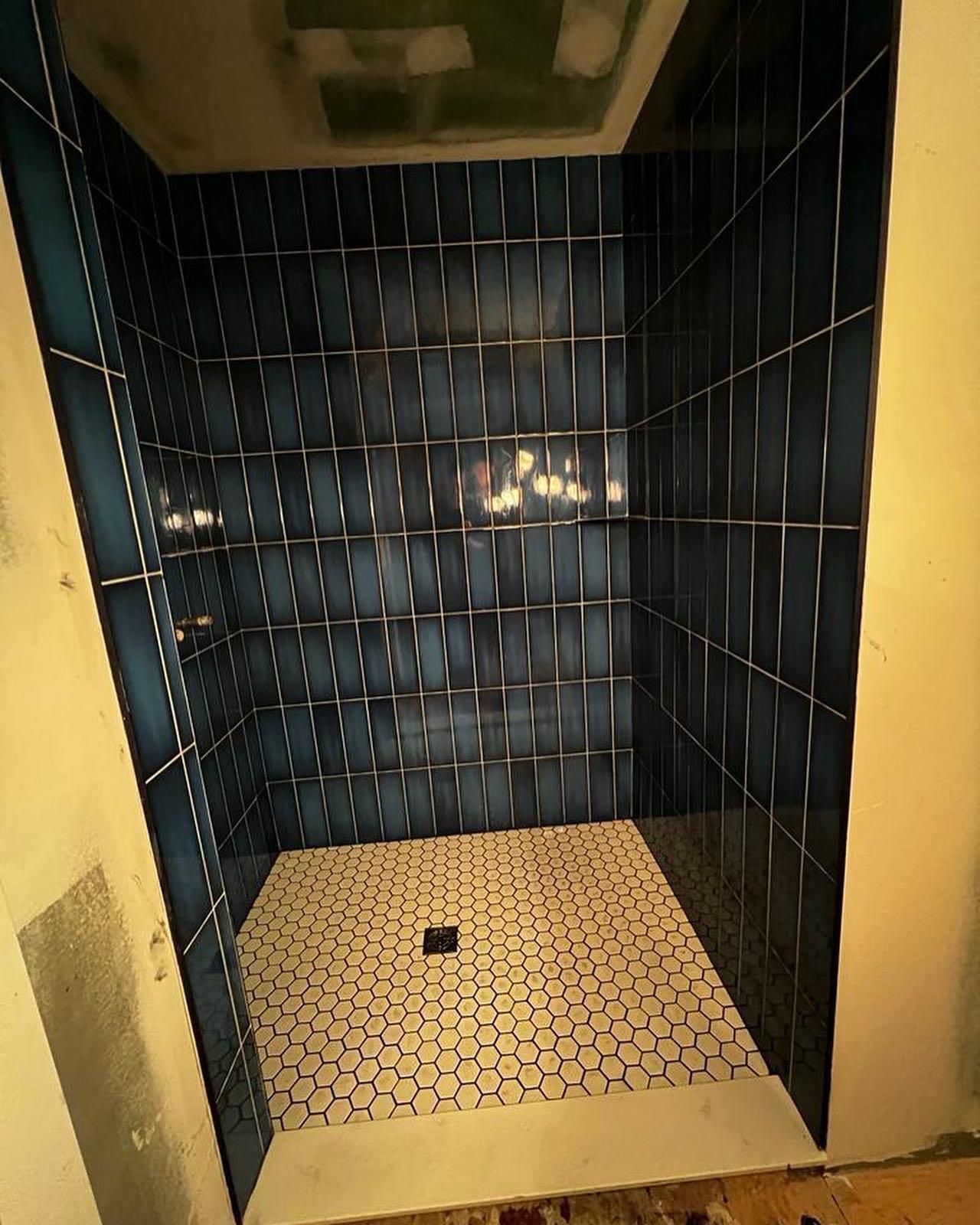 A shower stall with blue tiles and a white floor.