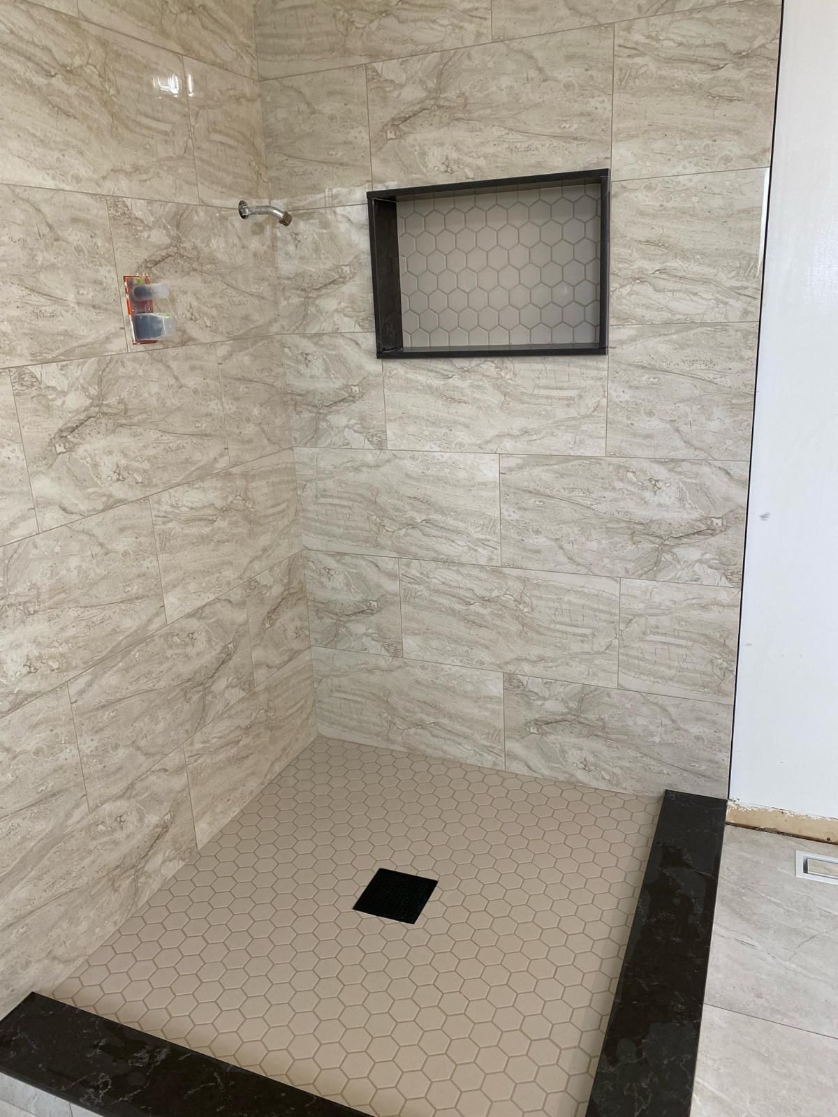 A bathroom with a walk in shower and a tiled wall.