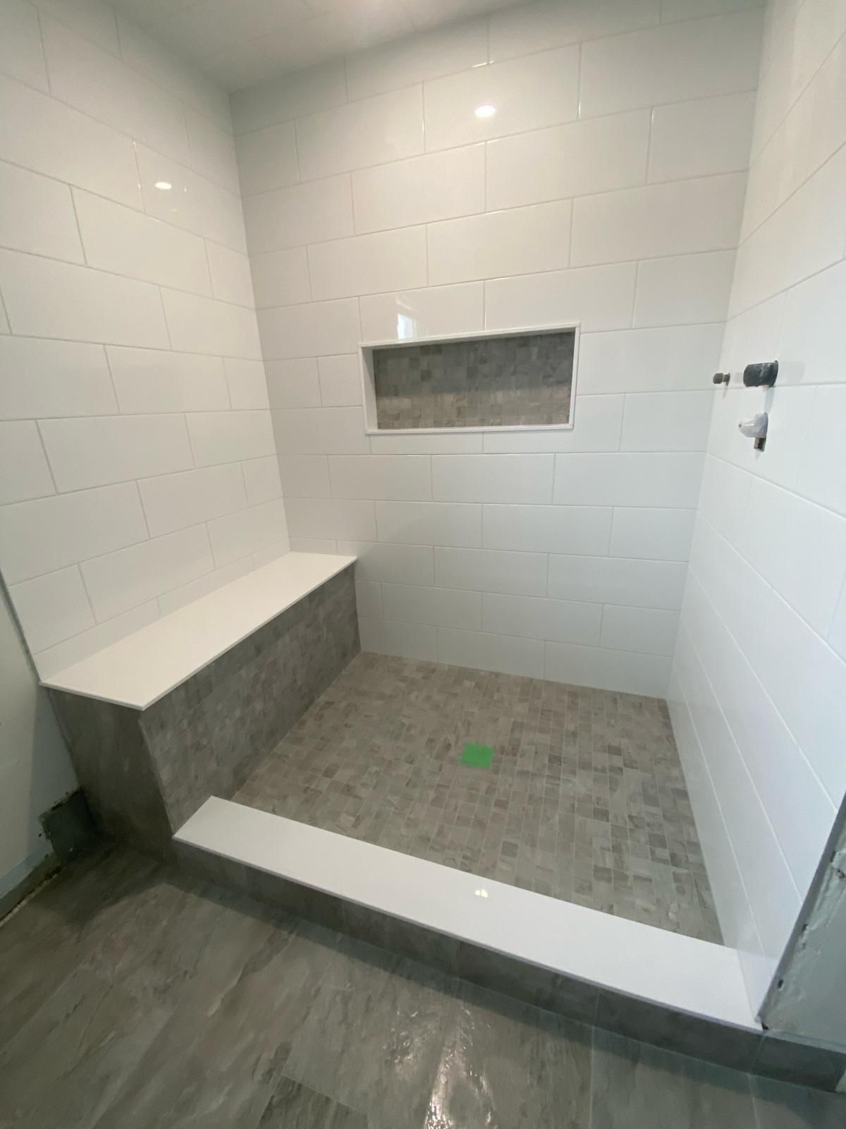 A bathroom with a walk in shower and a bench.