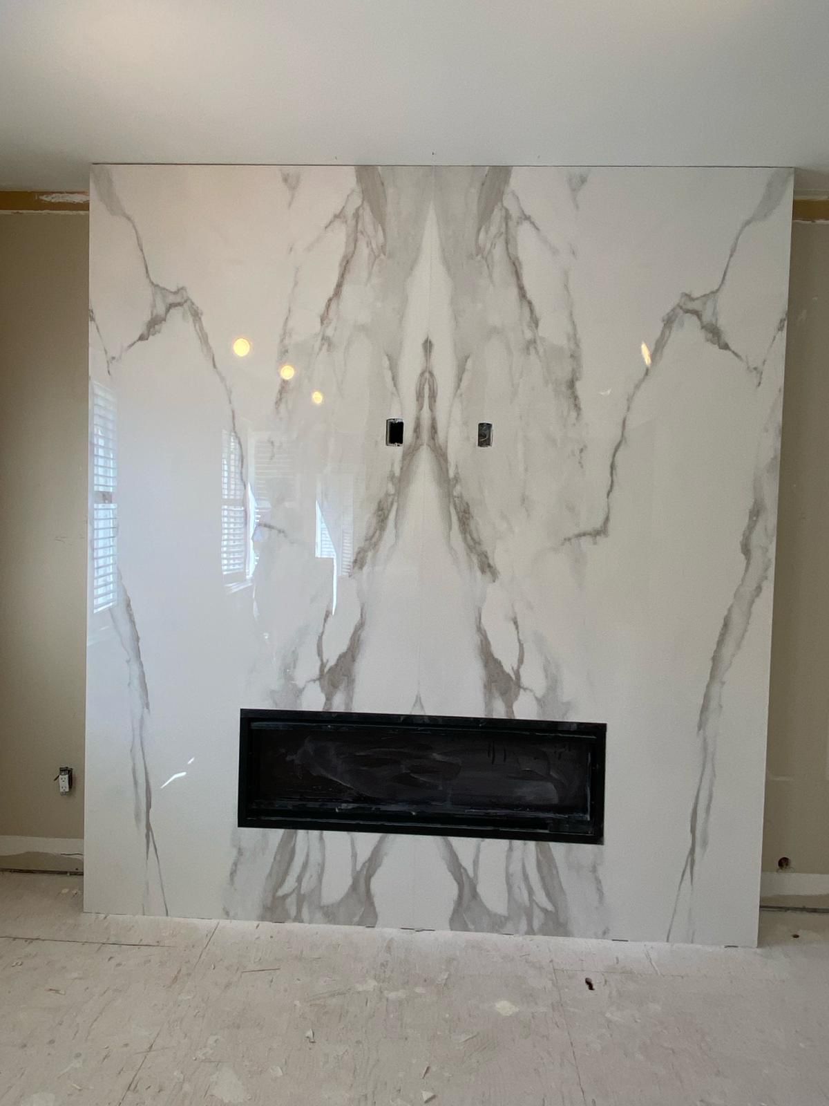 There is a fireplace in the middle of a marble wall.