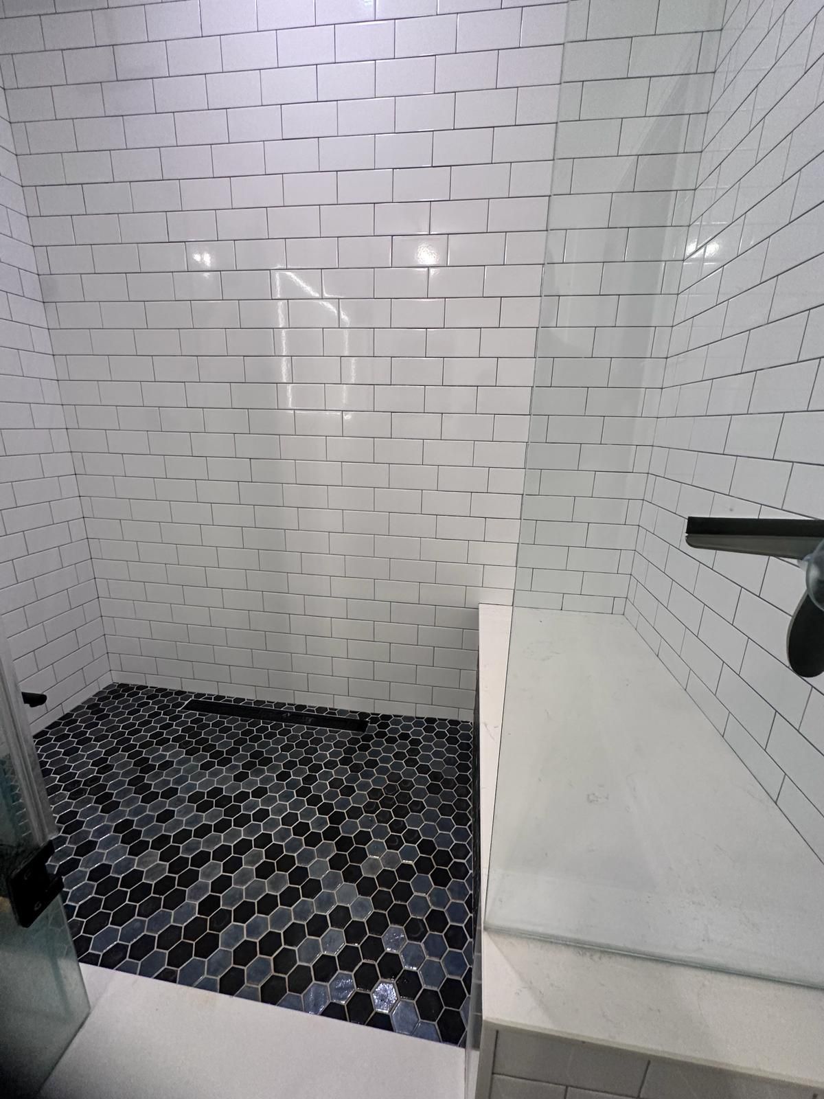 A bathroom with white brick walls and a black tile floor.