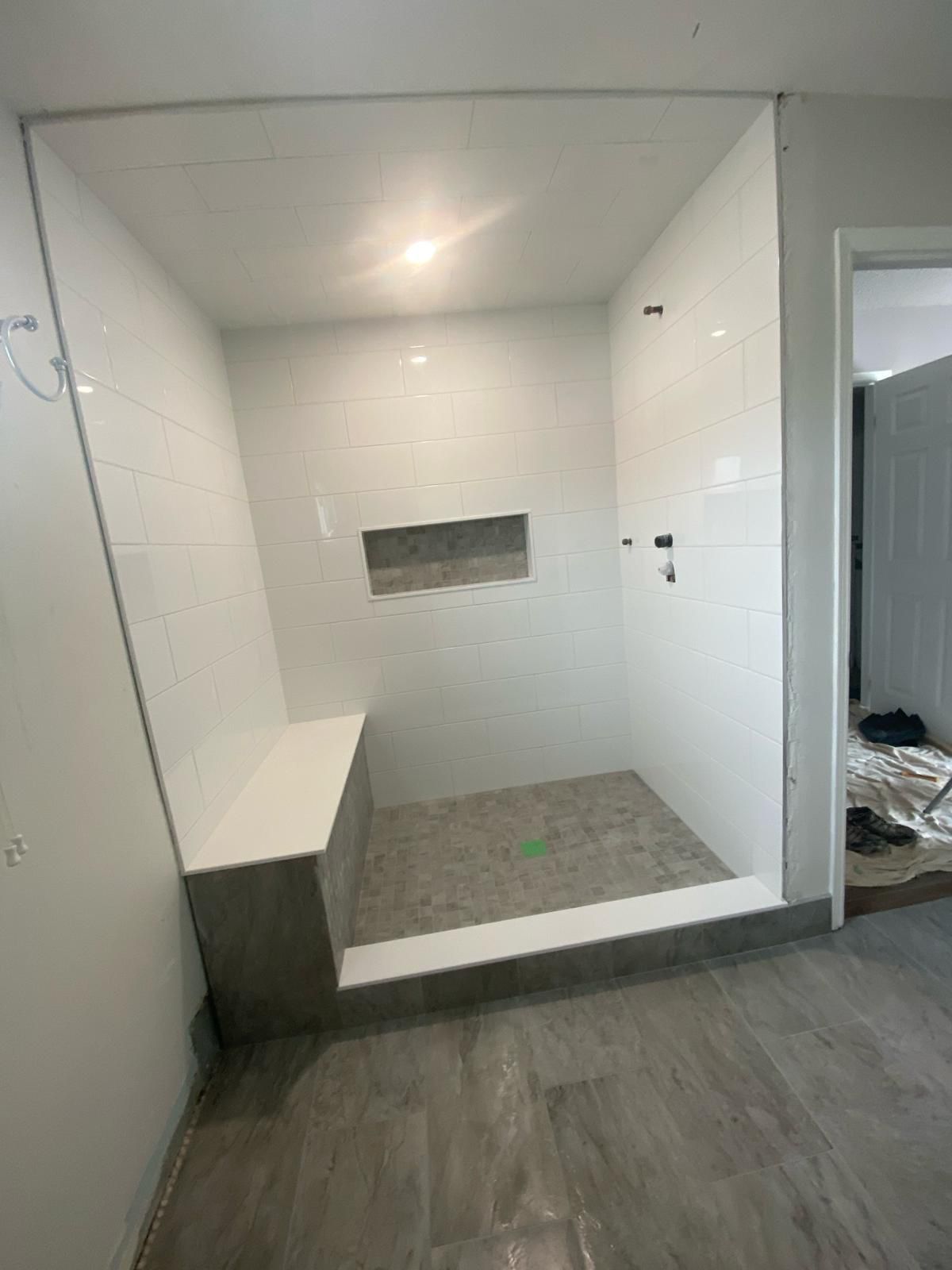 A bathroom with a walk in shower and a bench.