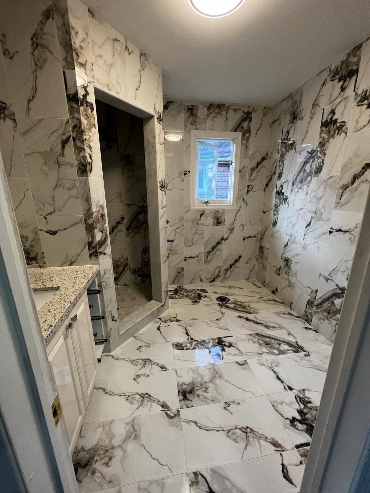 A bathroom with marble tiles on the walls and floor.