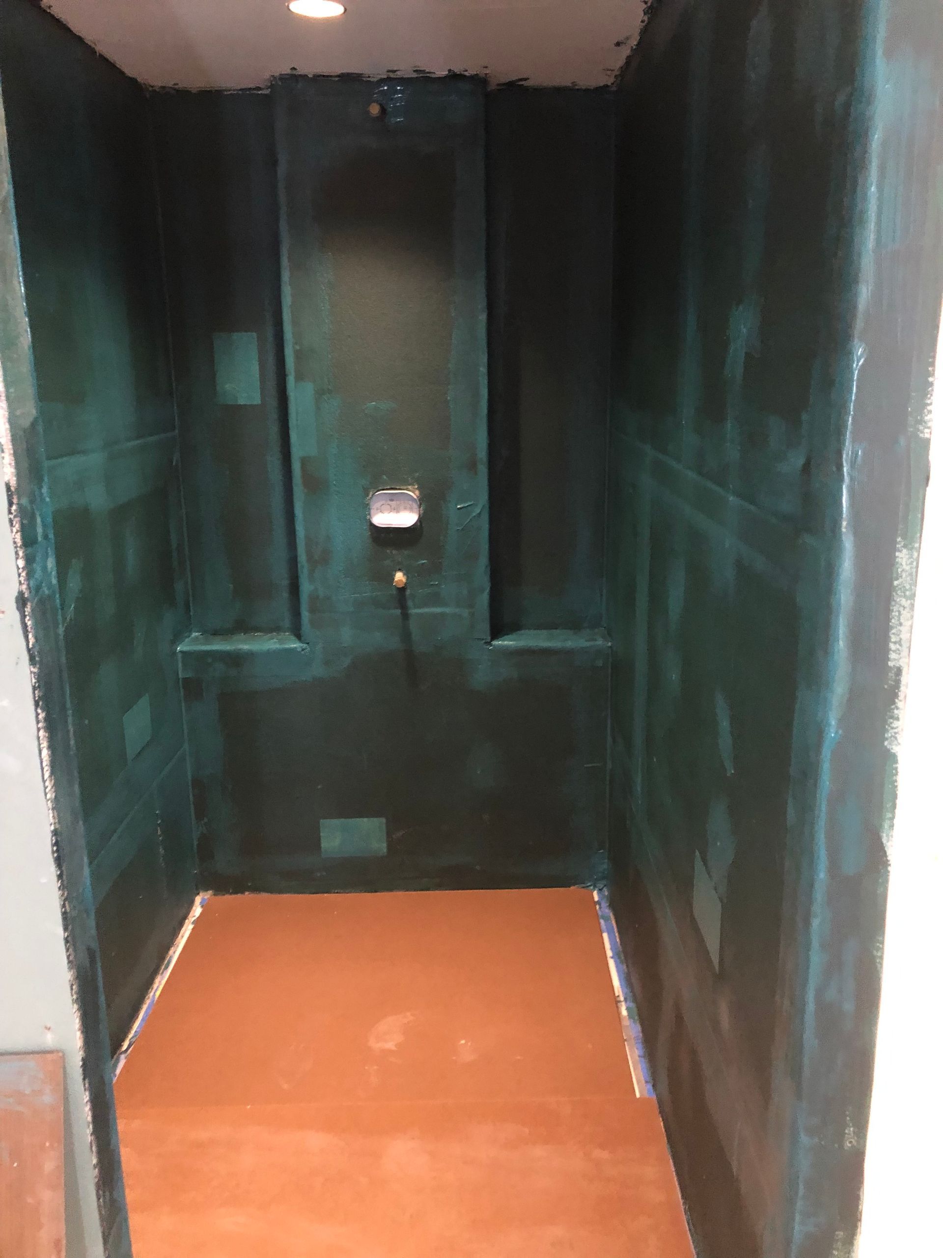 A room with green walls and a brown floor is being painted.