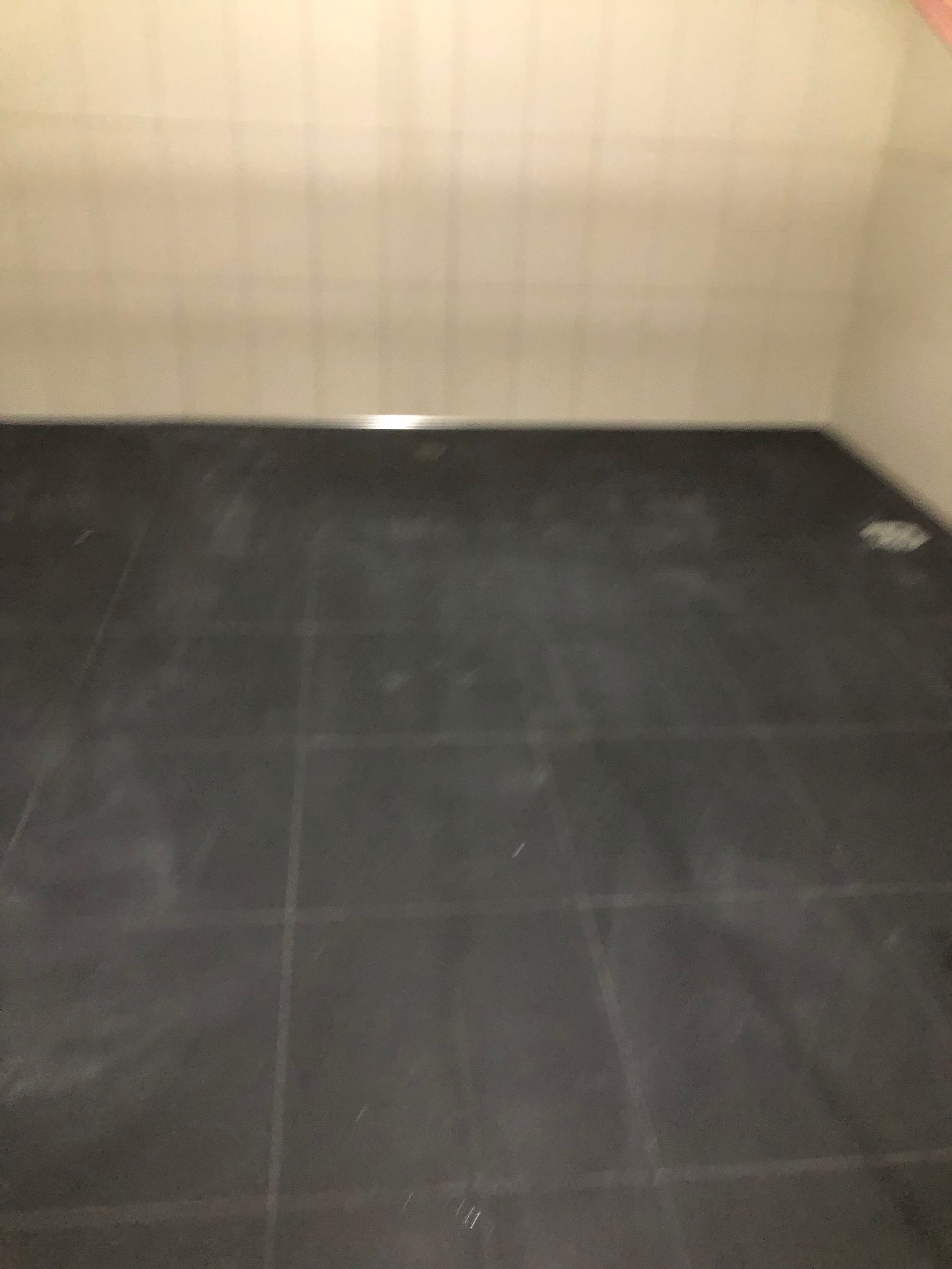 A black tiled floor in a room with a white wall.