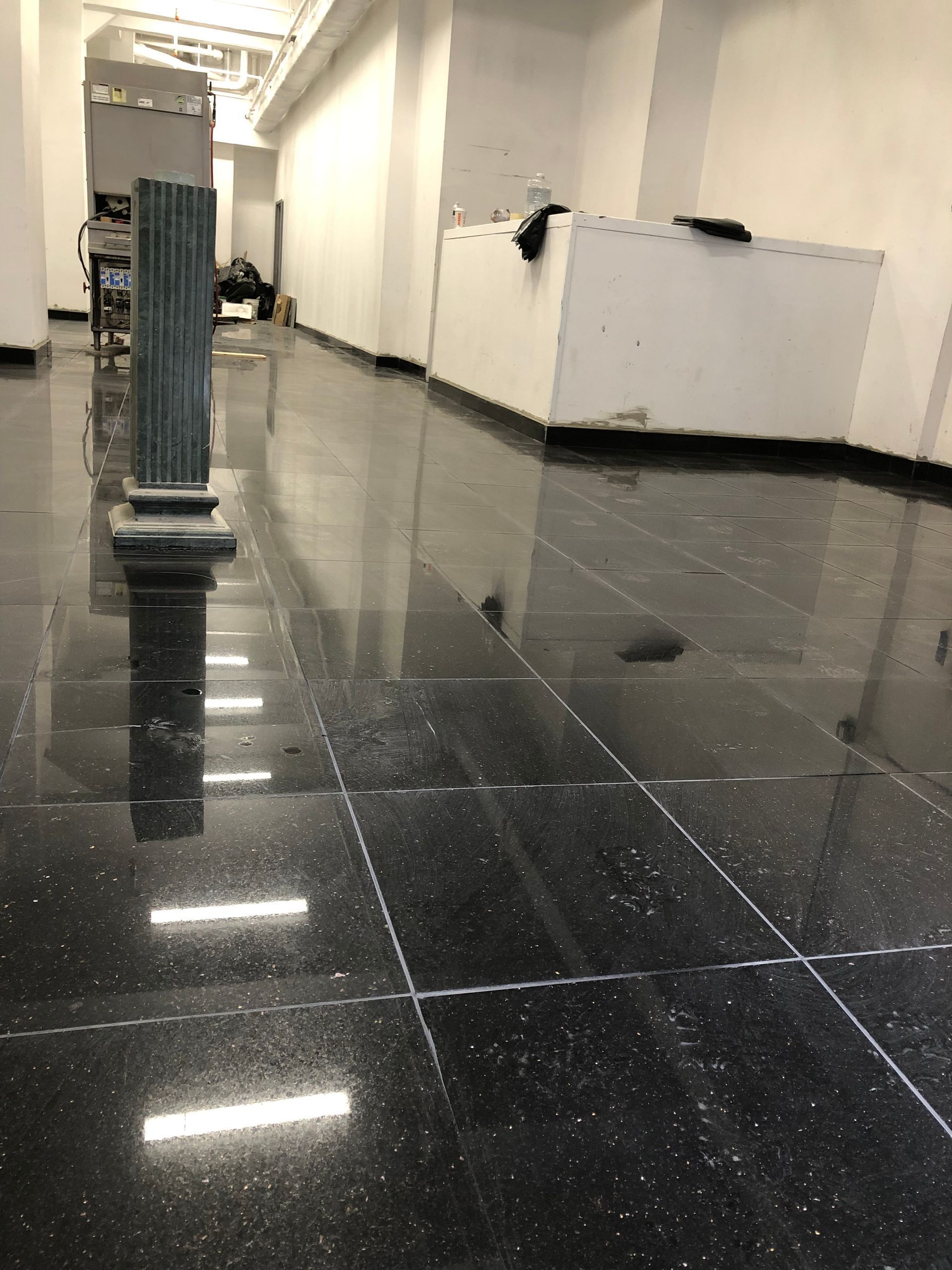 A hallway with a black tile floor and white walls.