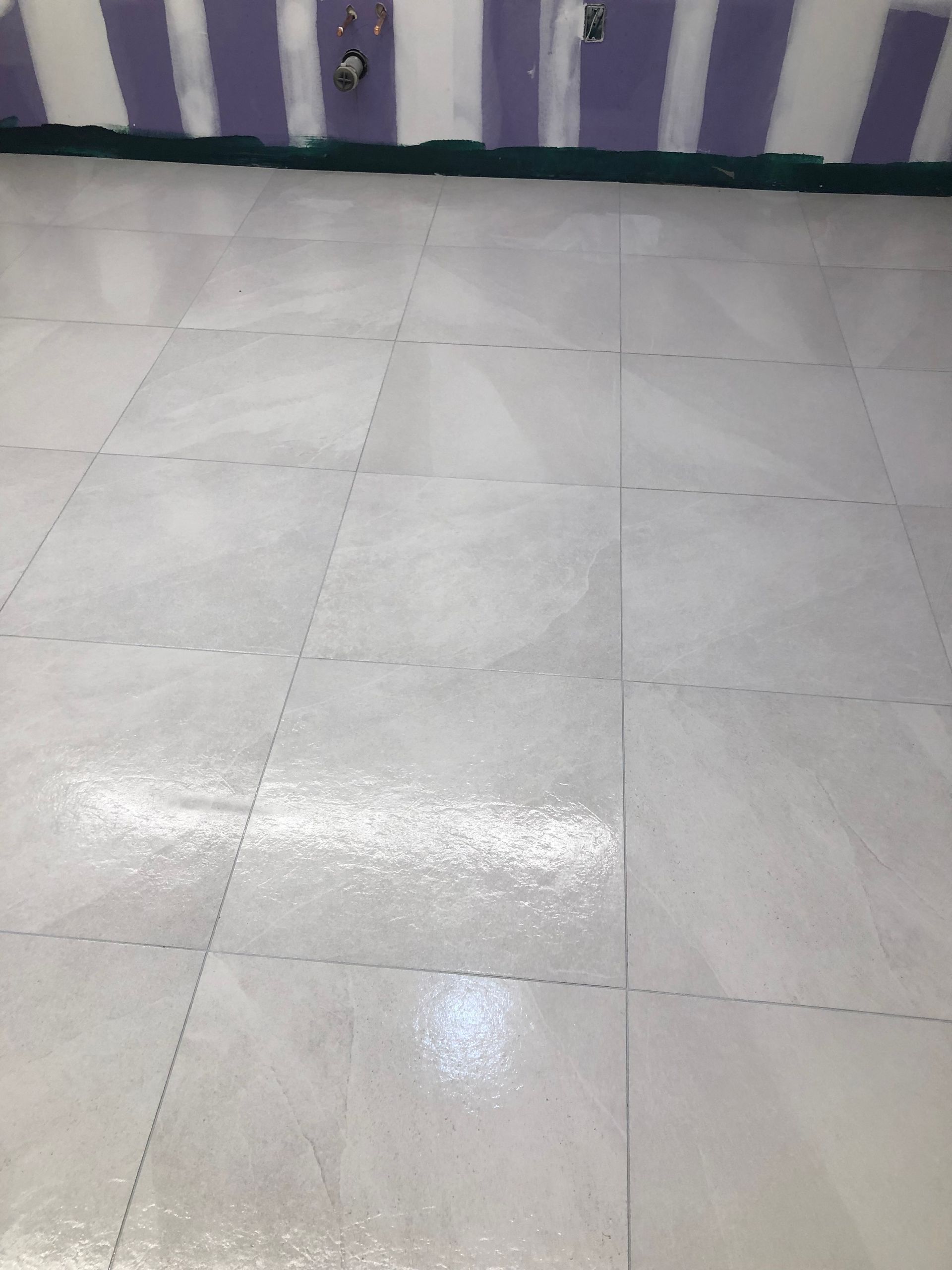 A white tile floor in a room with purple striped walls.