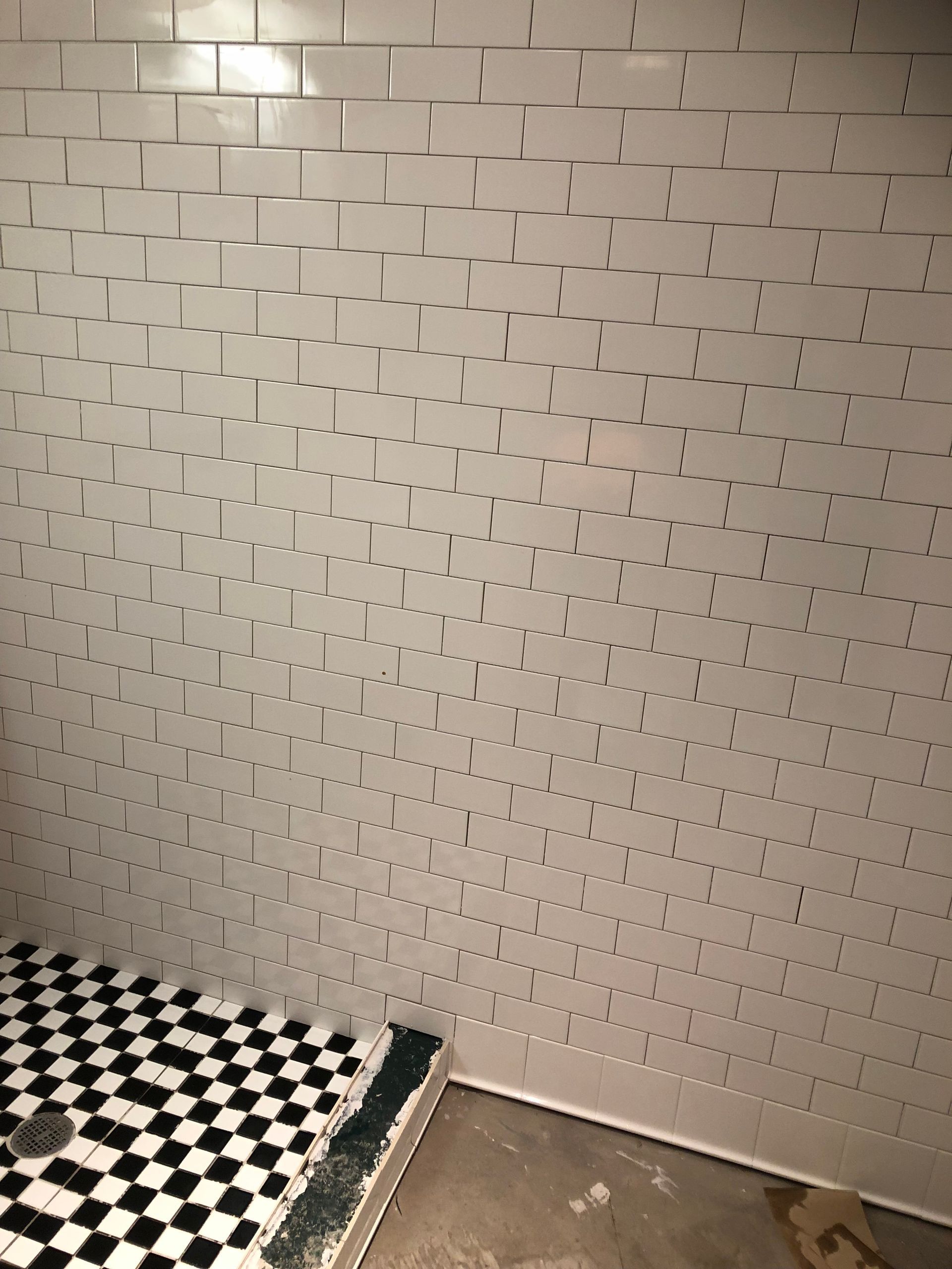 A bathroom with white tiles and a black and white checkered floor
