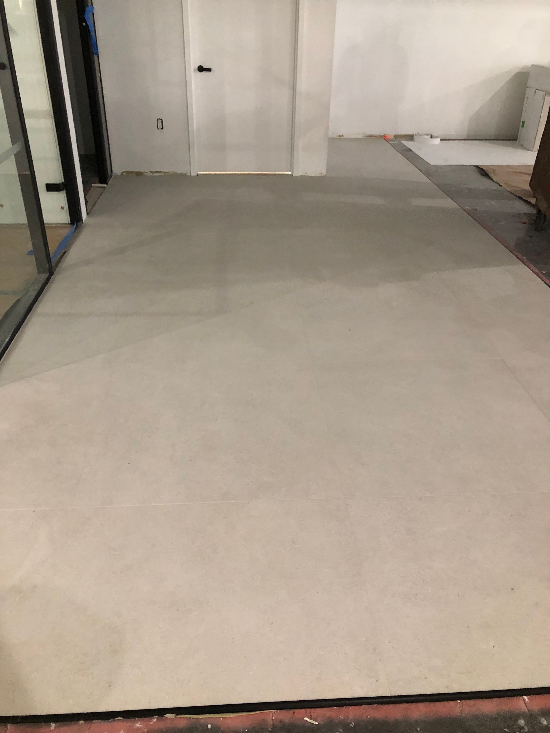 A large carpeted floor in a room with a door in the background.