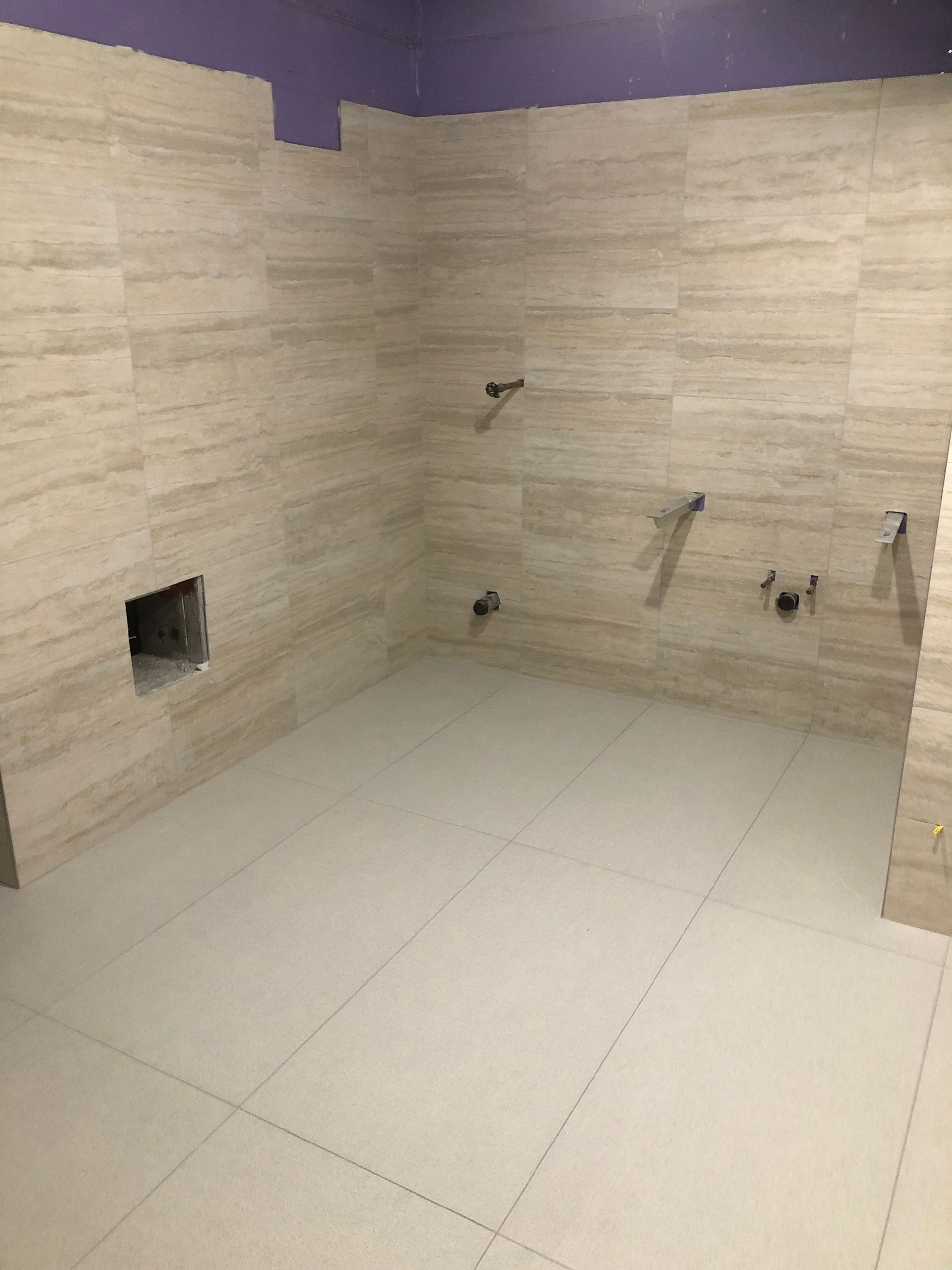 A bathroom with white tiles and a purple ceiling.