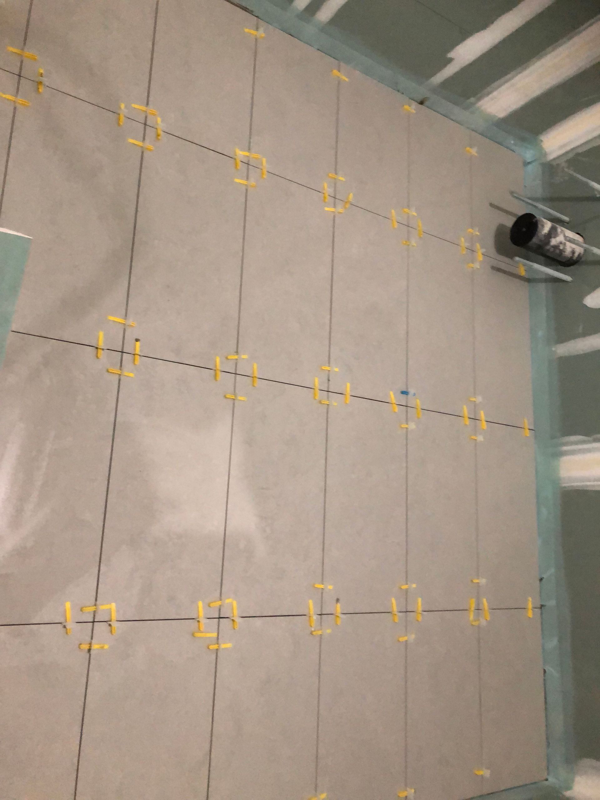 A row of tiles are being installed on a wall.