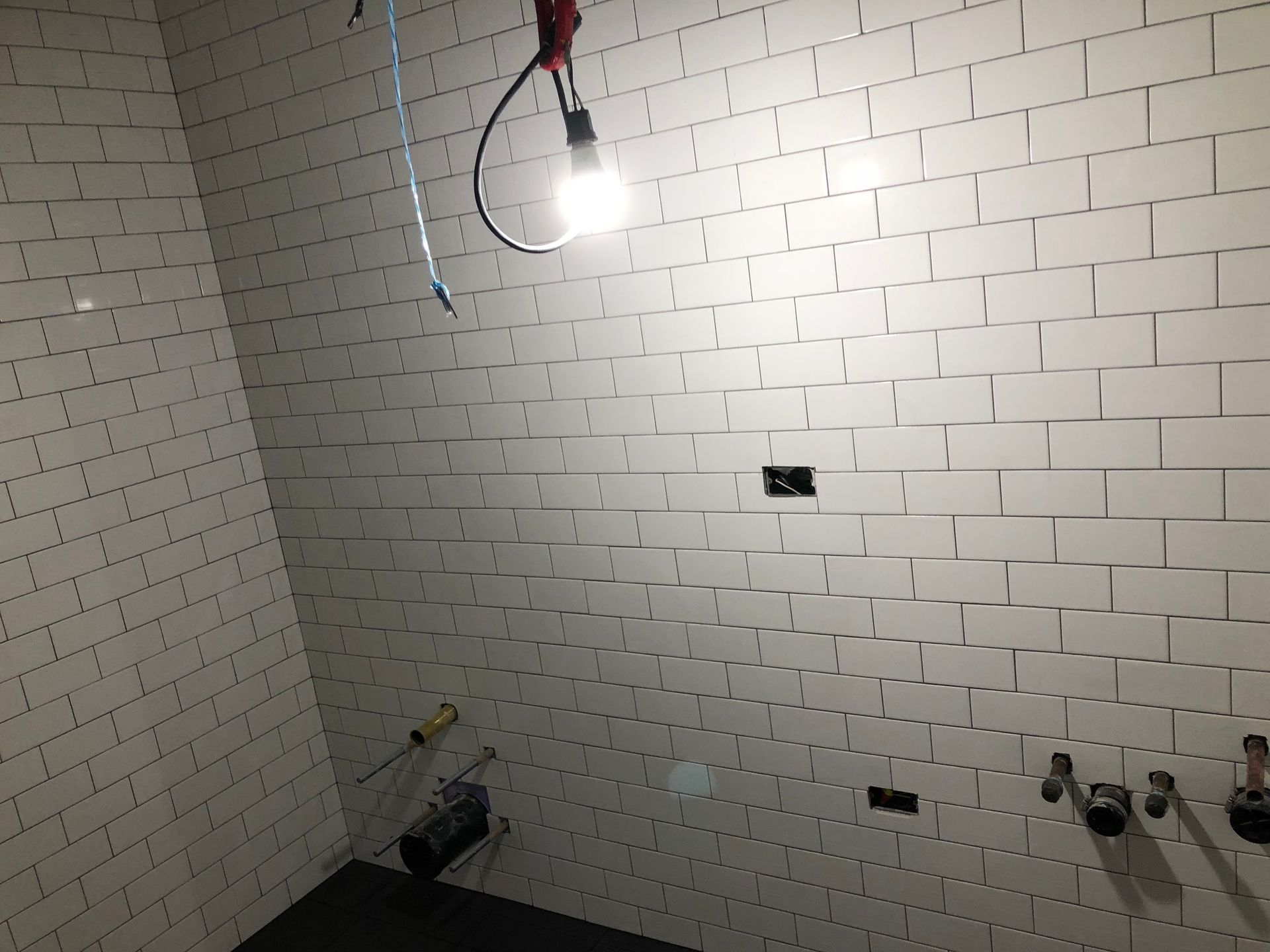 A bathroom with white tiles and a light hanging from the ceiling