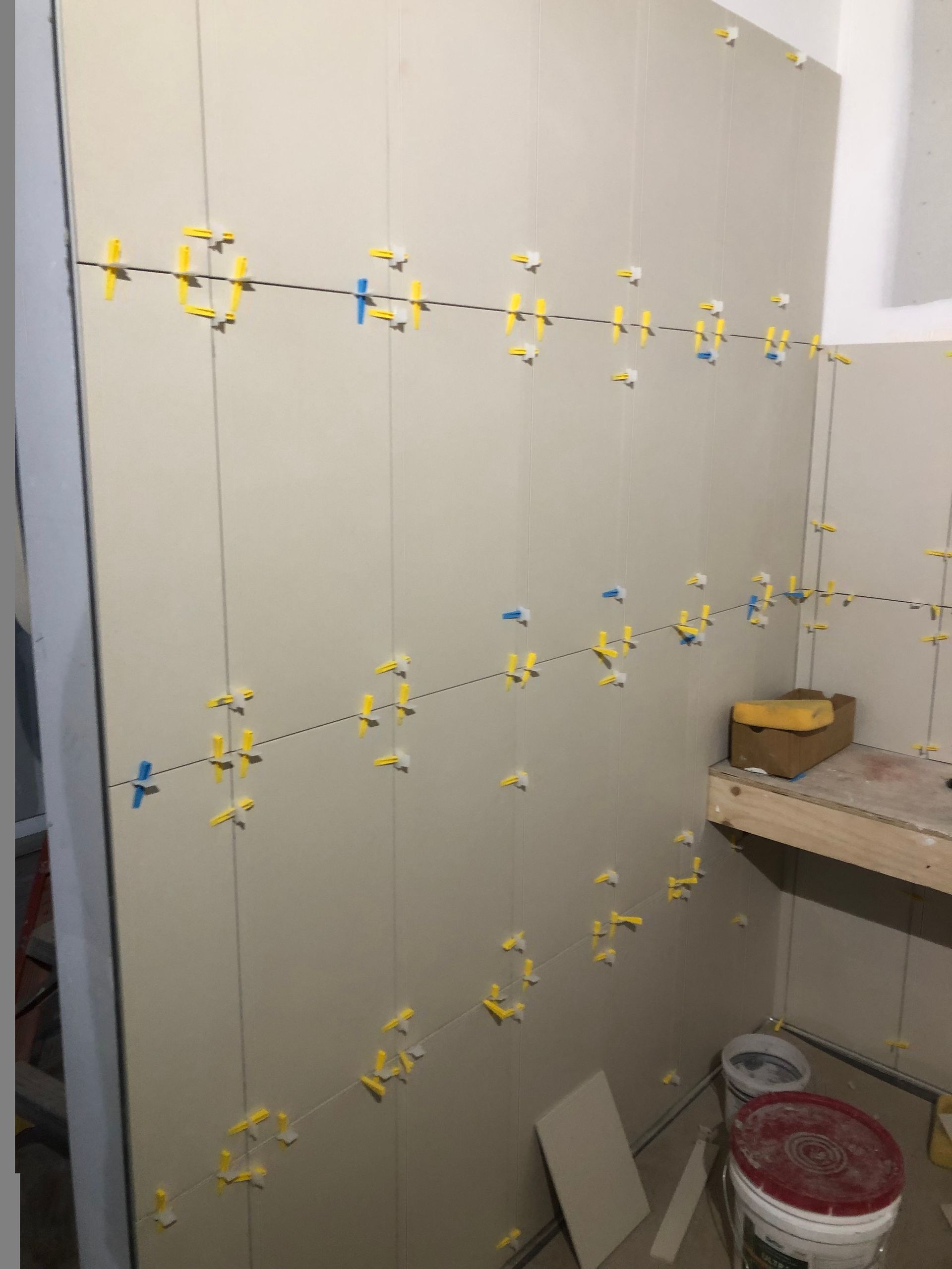 A bathroom with tiles being installed on the wall.