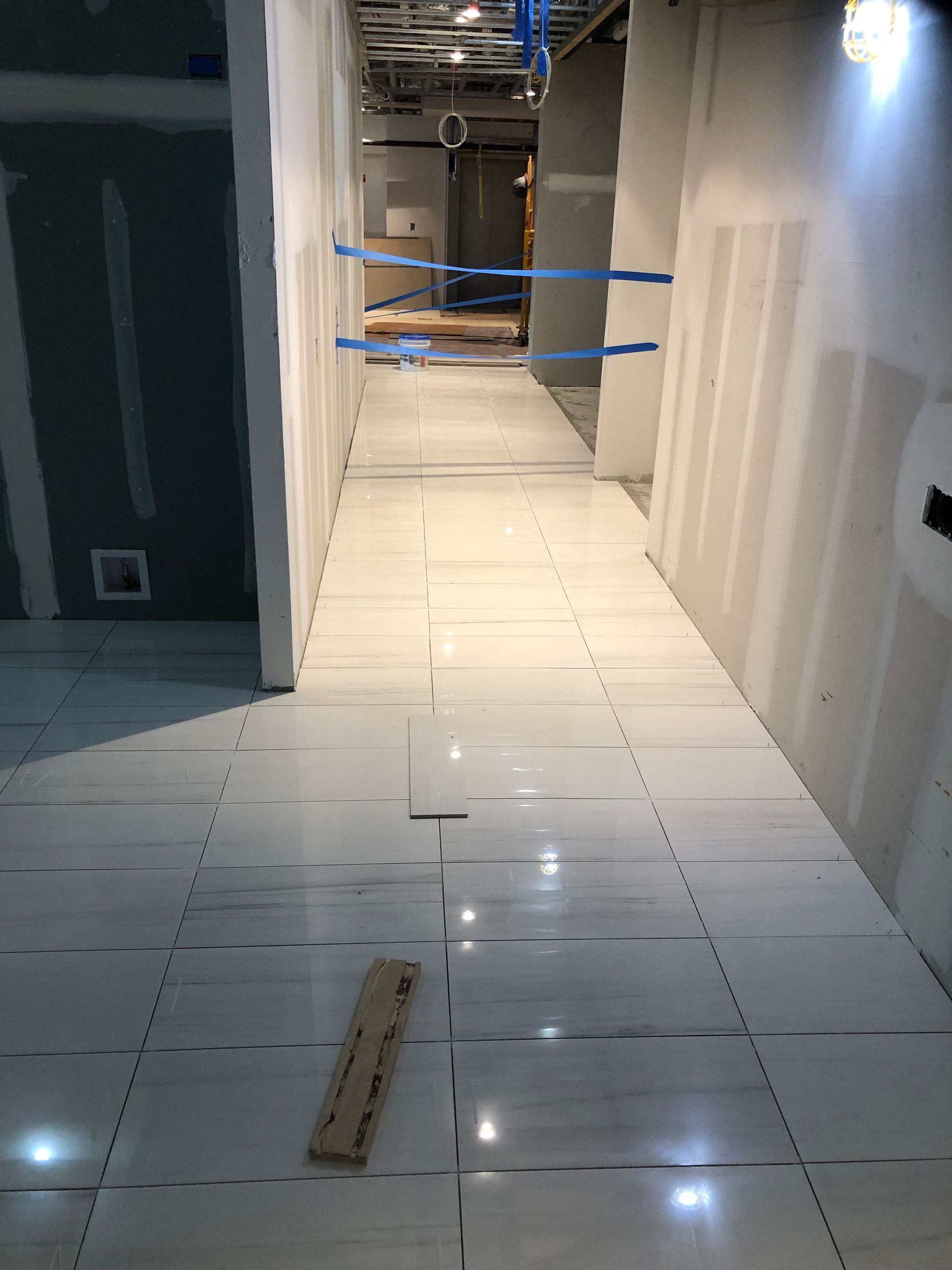 A long hallway with white tiles on the floor.
