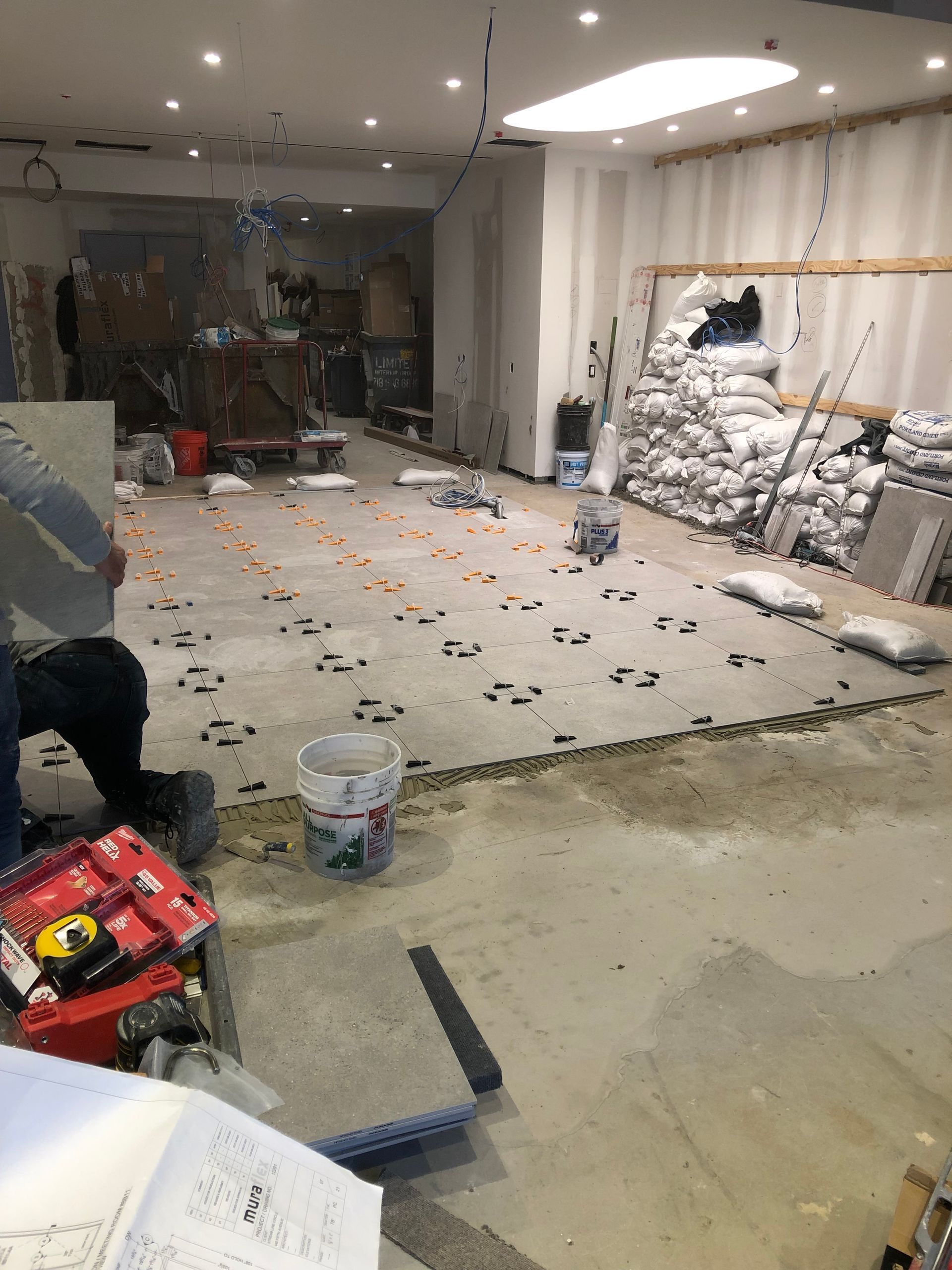 A man is sitting on the floor of a room being remodeled.