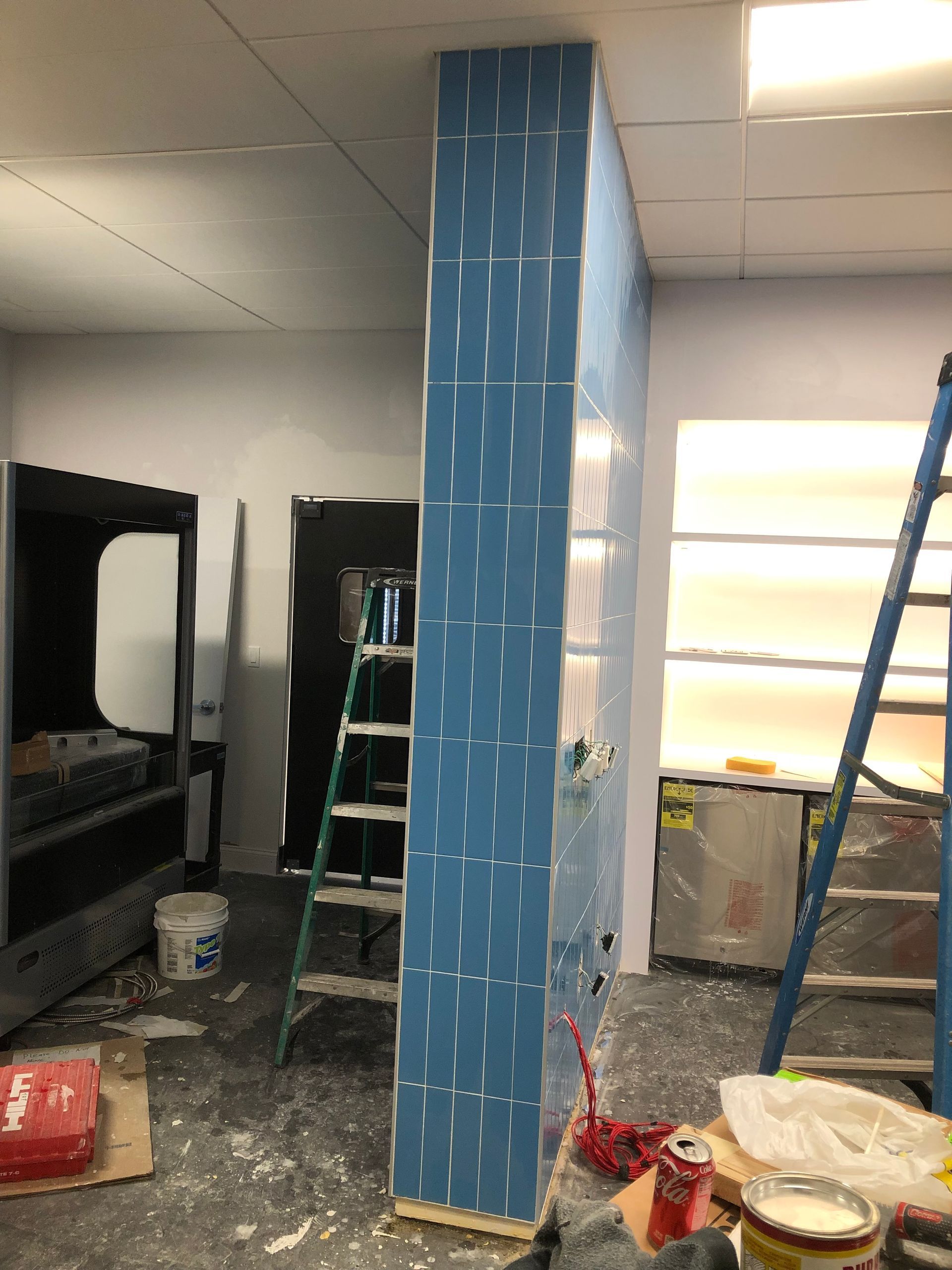 A room with a blue pillar and a ladder in it.