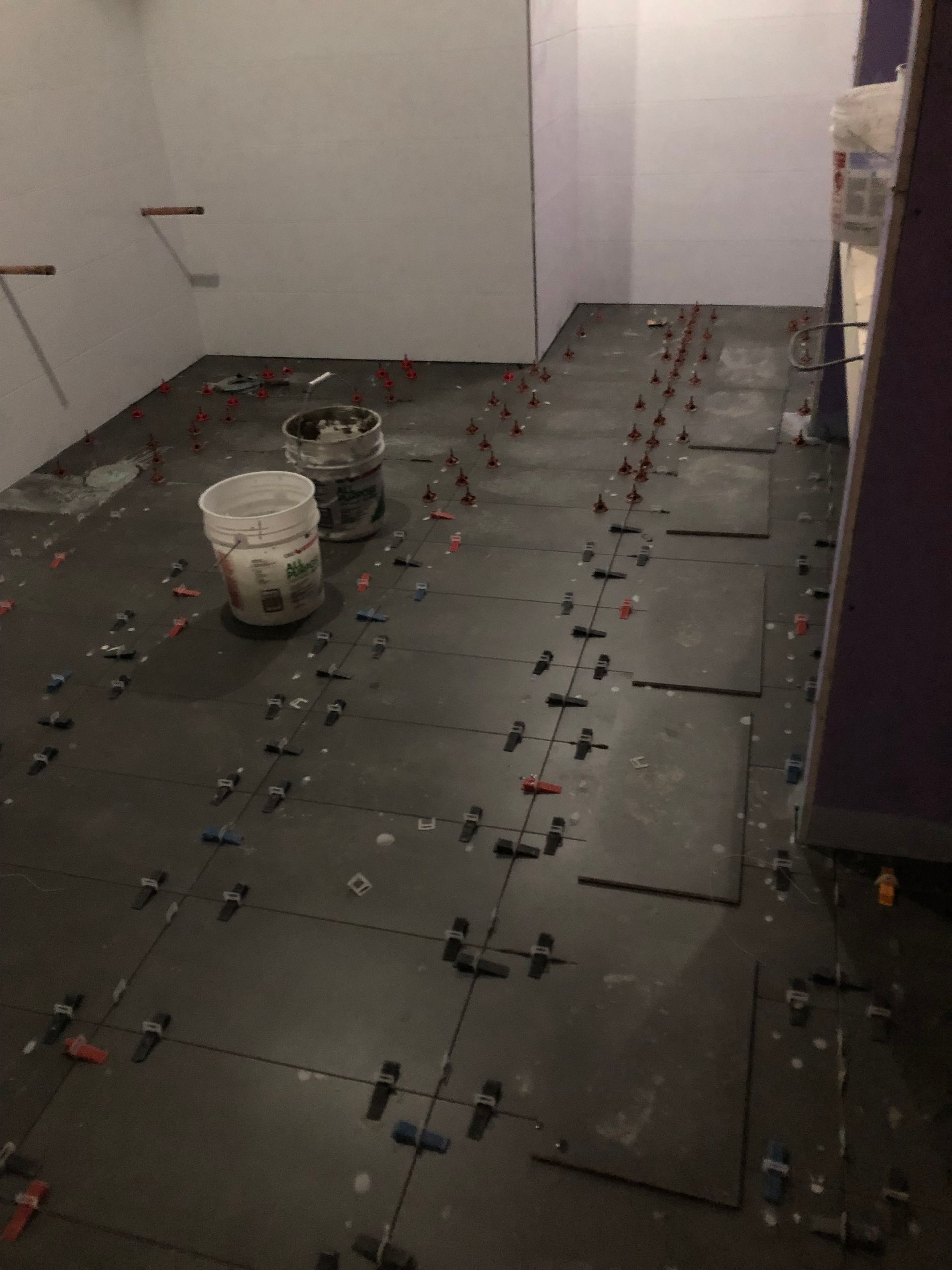 A room with a lot of tiles and buckets on the floor.