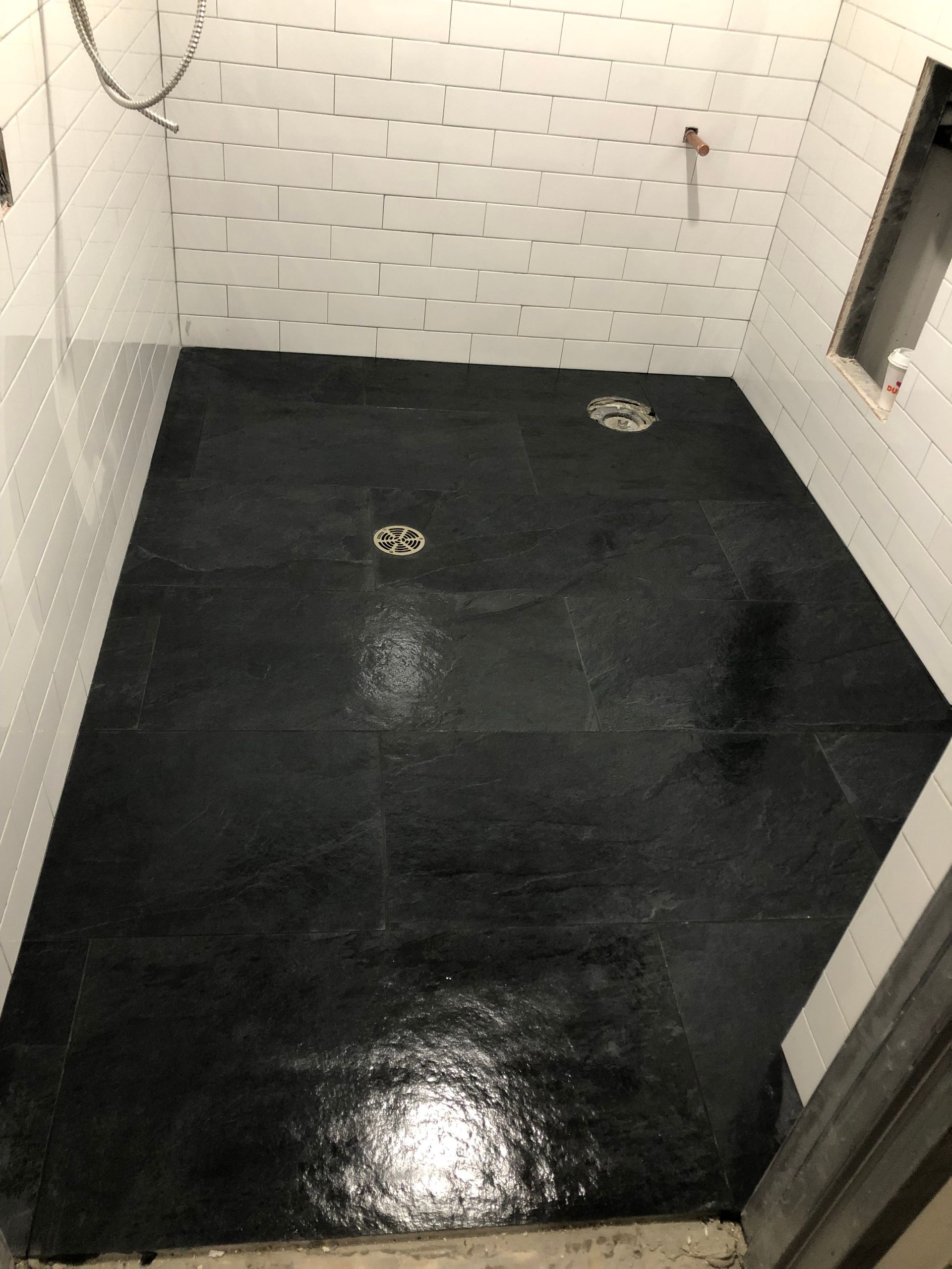 A black tile floor in a bathroom with white tiles