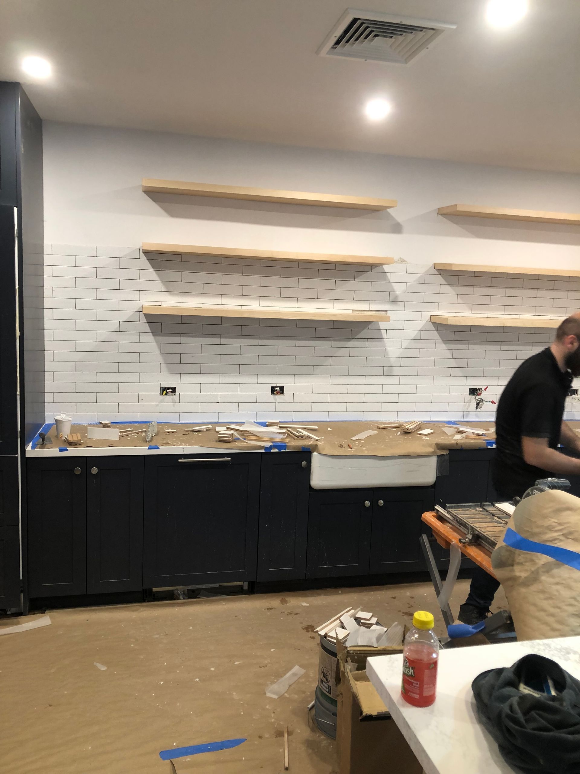 A man is working in a kitchen with a sink and shelves