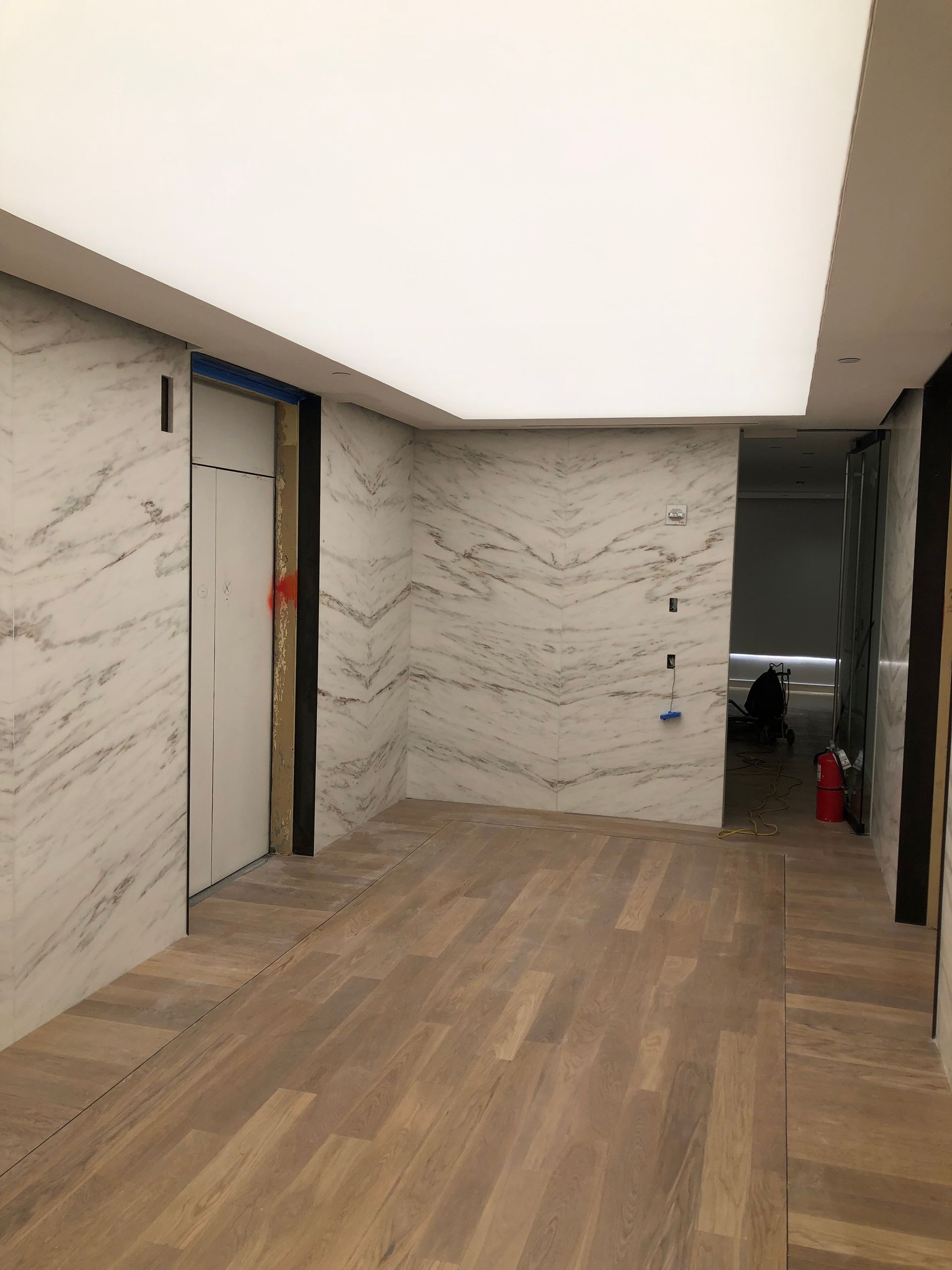 An empty room with a wooden floor and marble walls.