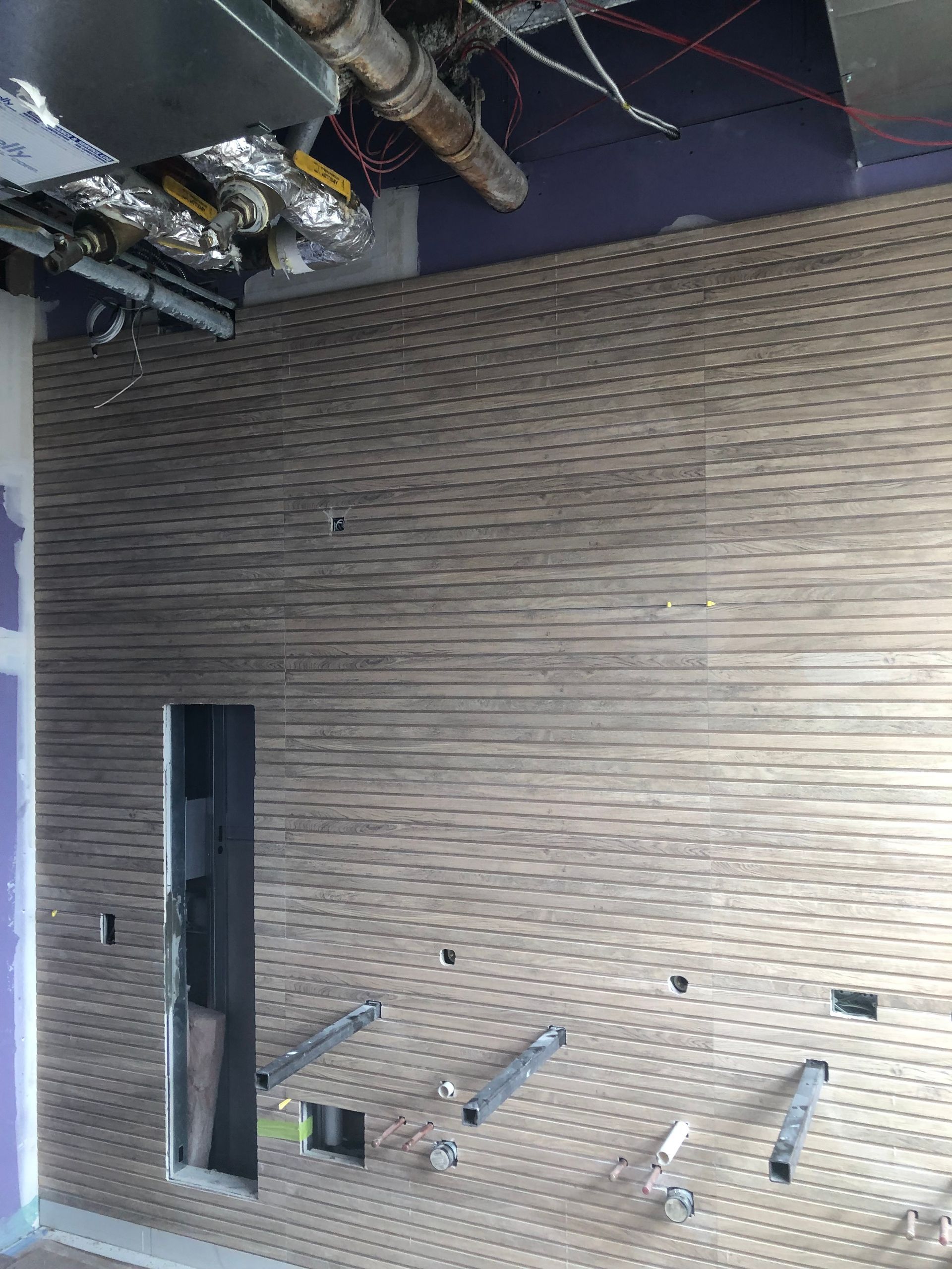 A room with a brick wall and pipes hanging from the ceiling.