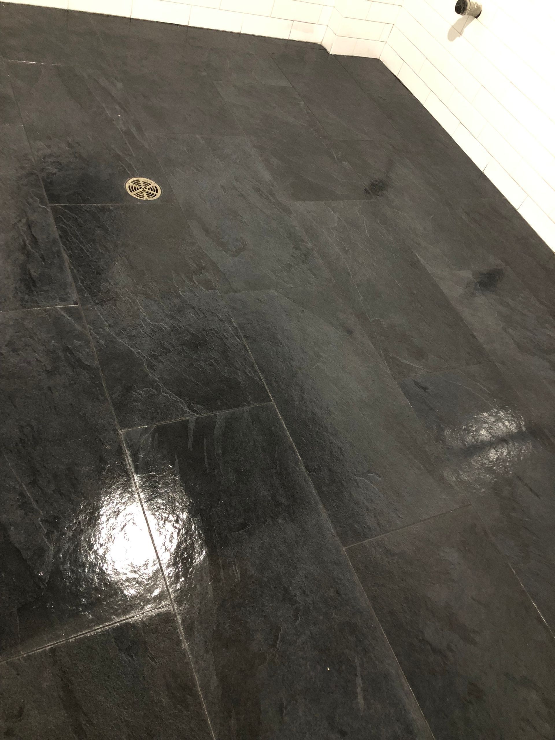 A close up of a black tile floor with a drain.