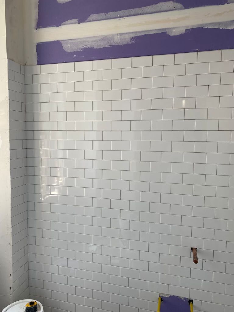 A bathroom with white tiles and a purple wall