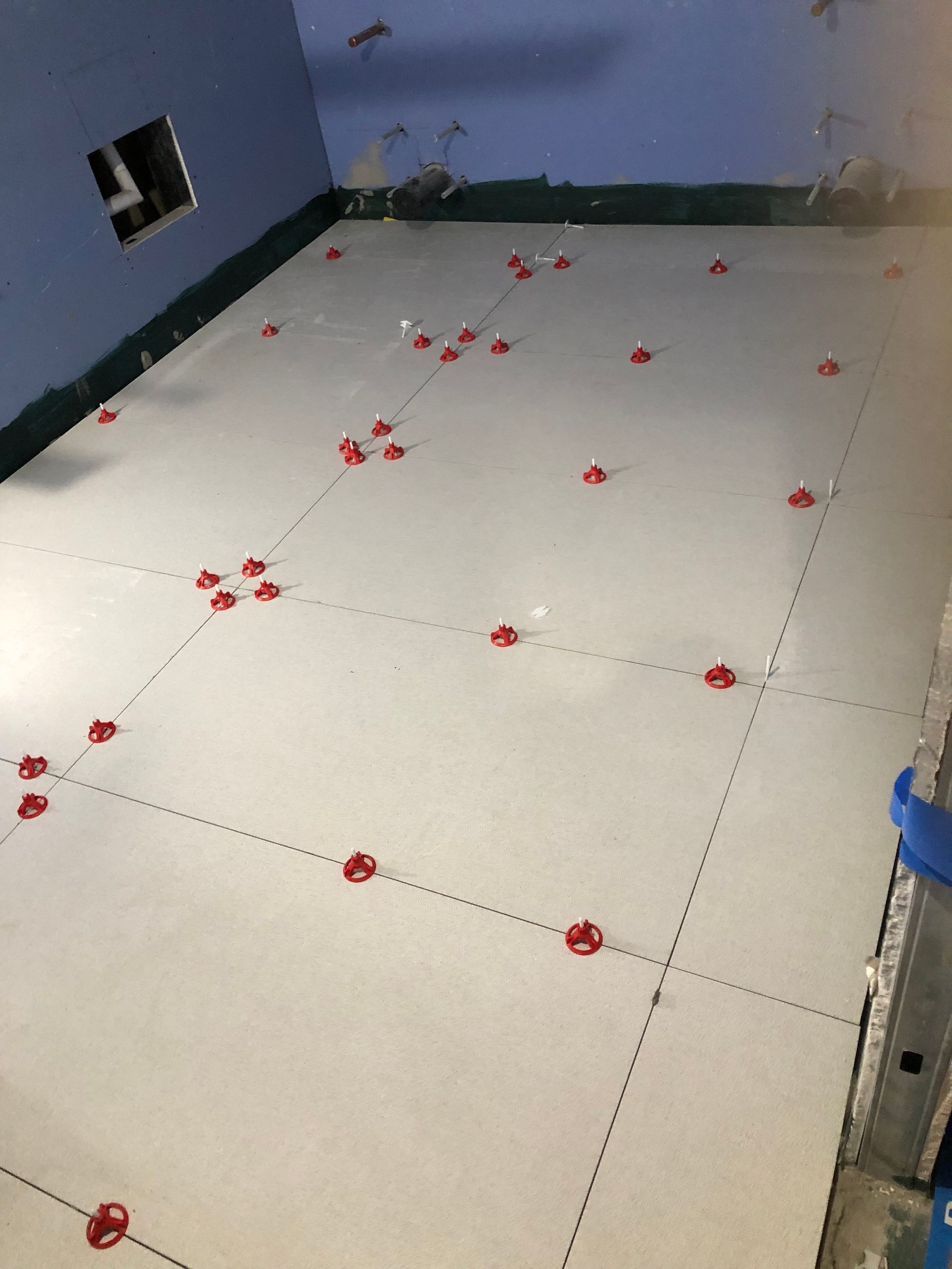 A white tile floor with red spacers on it